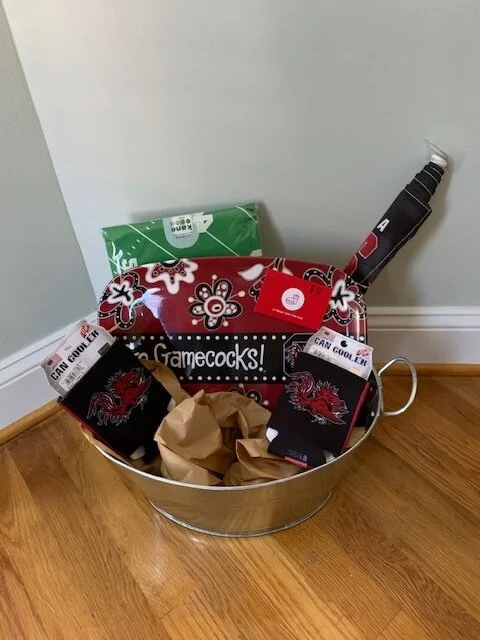 “HAIL TO THEE” BASKET Enjoy serving your fellow fans and friends with this cute platter, and $50 to get a delicious tray of nuggets from Chick-Fil-A Keep your drinks cold with these koozies and your car decked out with a black out flag. You’ll be ready for another game like the one where we beat UGA. DONOR: 2nd Grade Classes VALUE: $115