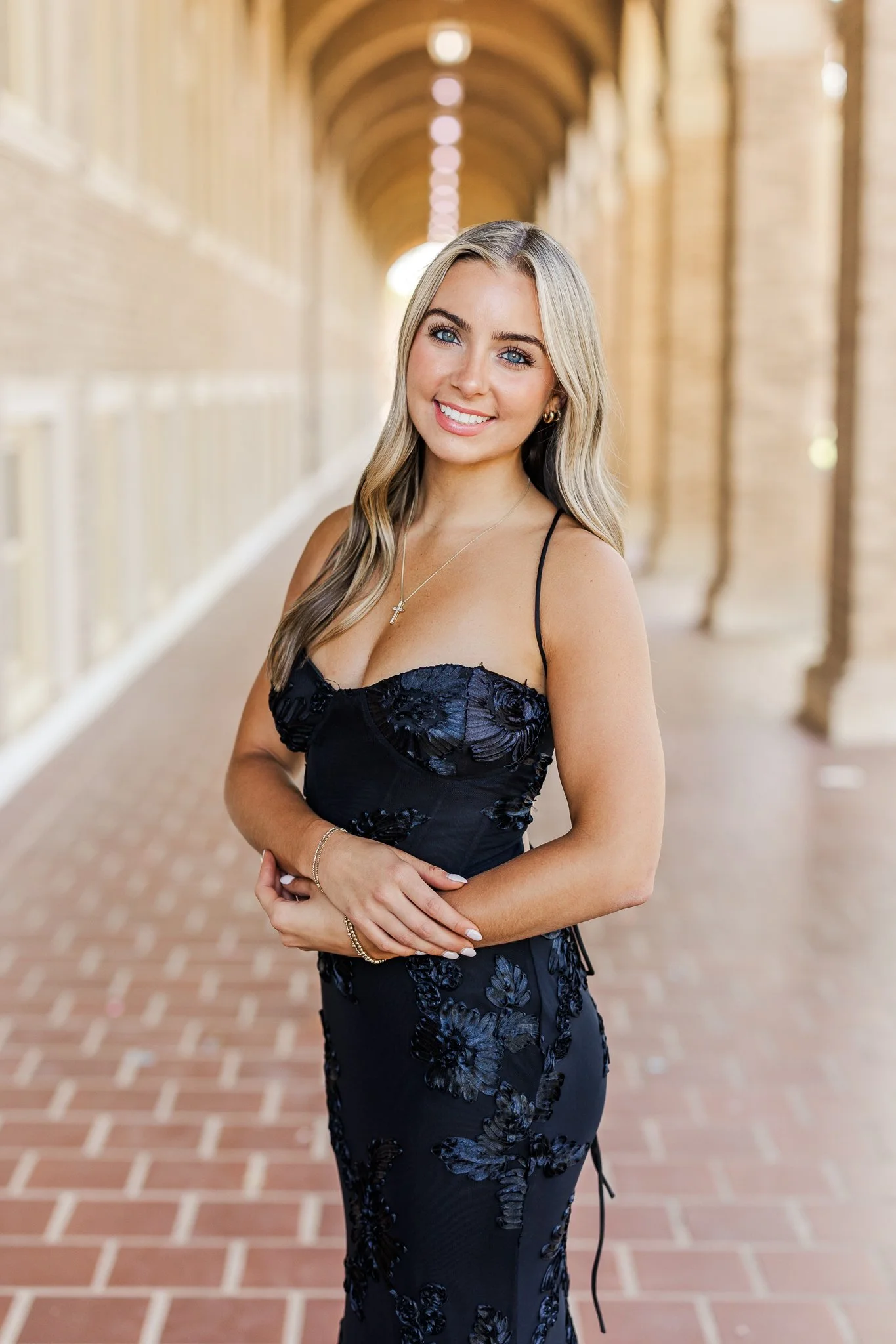 a texas tech senior girl wearing a black formal dress while posing her hand across her body under a popular spot on campus.