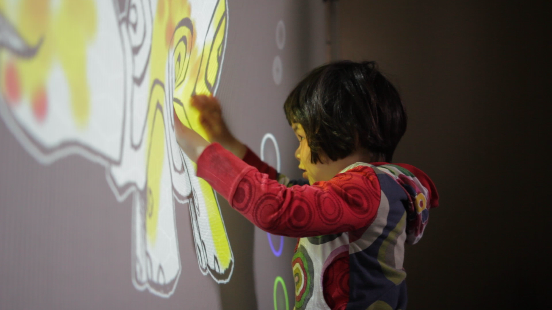 Ara playing with the sensorySURFACE | stretchCOLOR prototype, where pressure applied to the 2D textile determines the color being projected onto the surface.