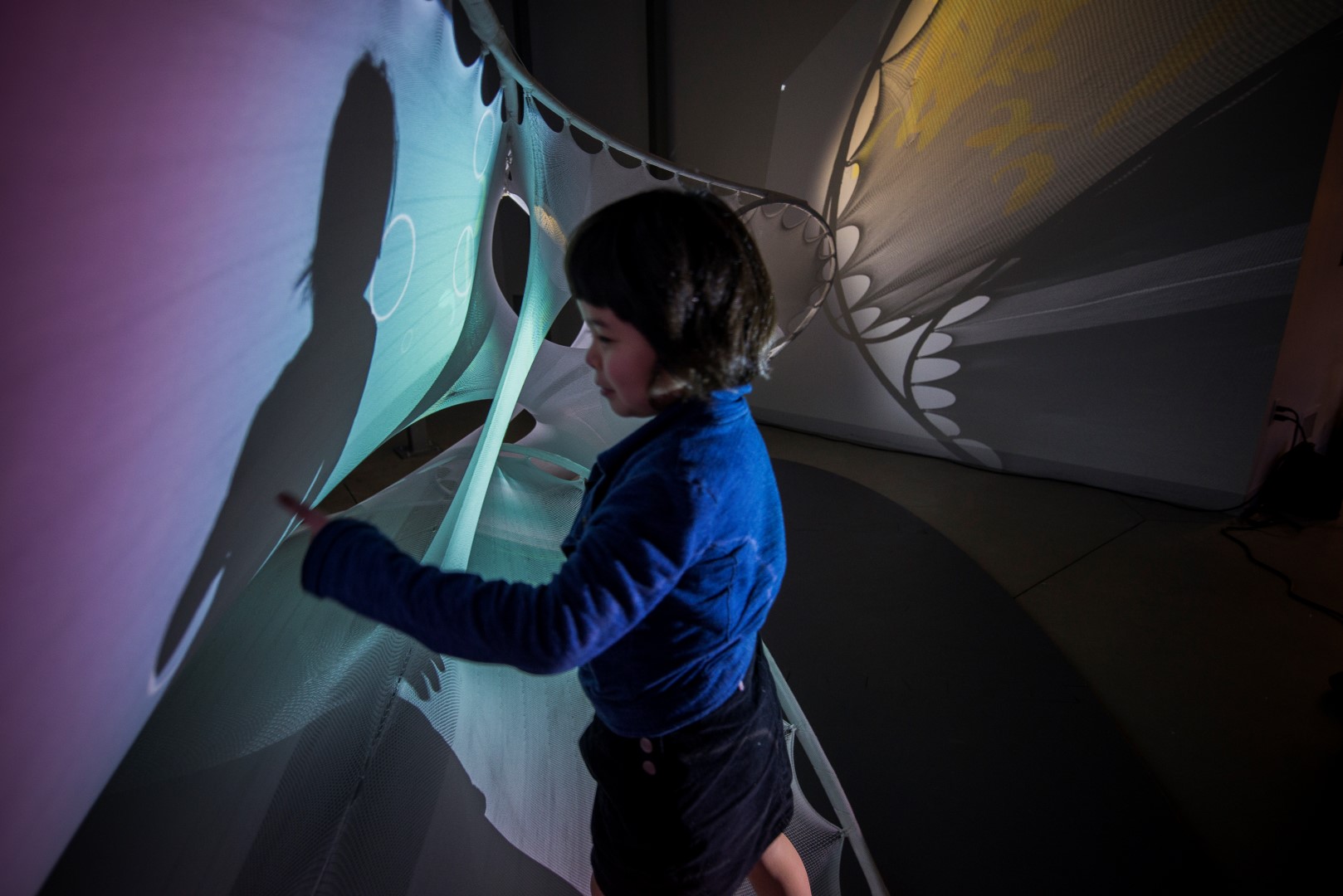 Ara playing with the sensoryPLAYSCAPE | stretchSWARM prototype which combines textile-hybrid technology with an interface for interacting with swarms of fish.