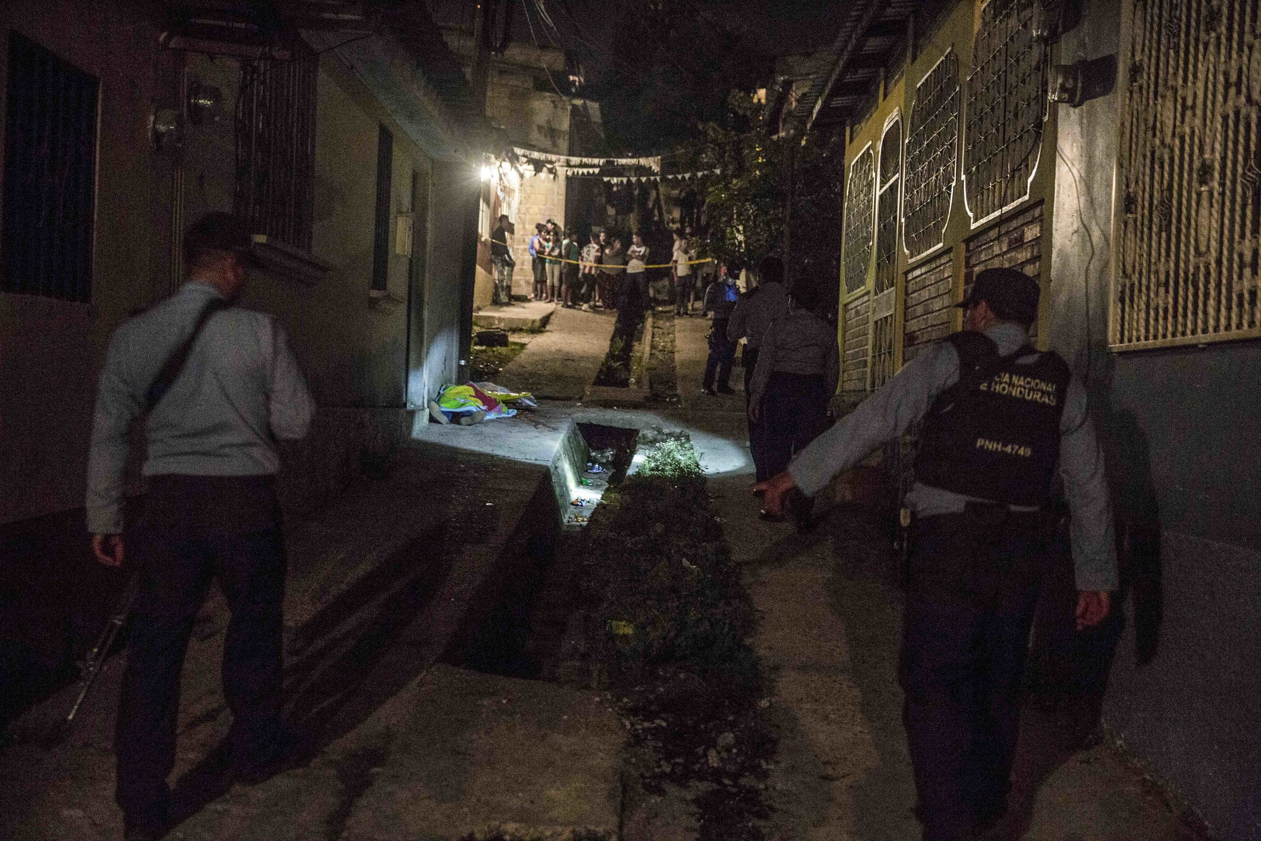 Honduran police officers guard the corpse of a woman, who was killed along with three others and a boy, apparently as a result of drug-related issues, in one of the districts of the capital Tegucigalpa.