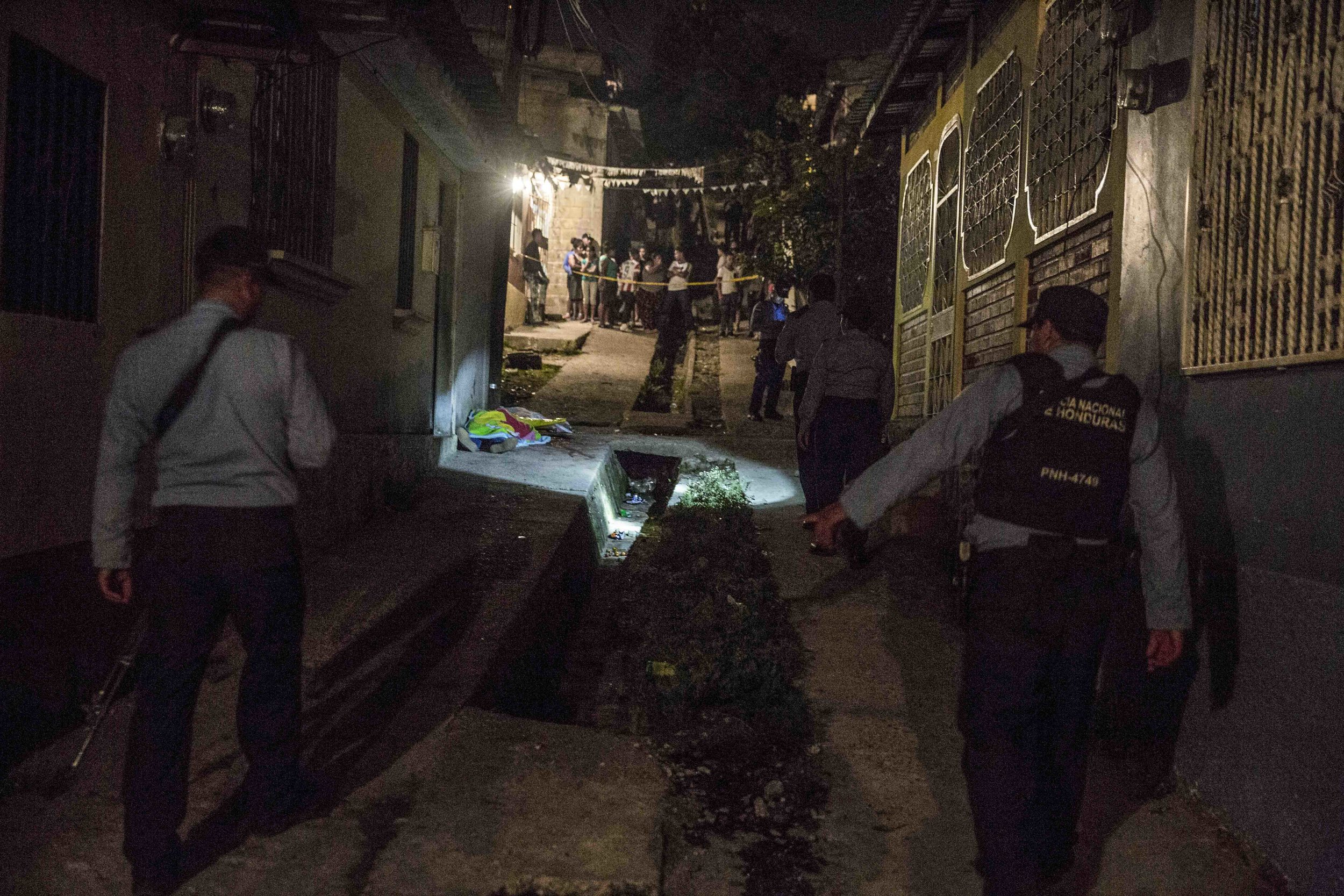  Honduran police officers guard the corpse of a woman, who was killed along with three others and a boy, apparently as a result of drug-related issues, in one of the districts of the capital Tegucigalpa. 