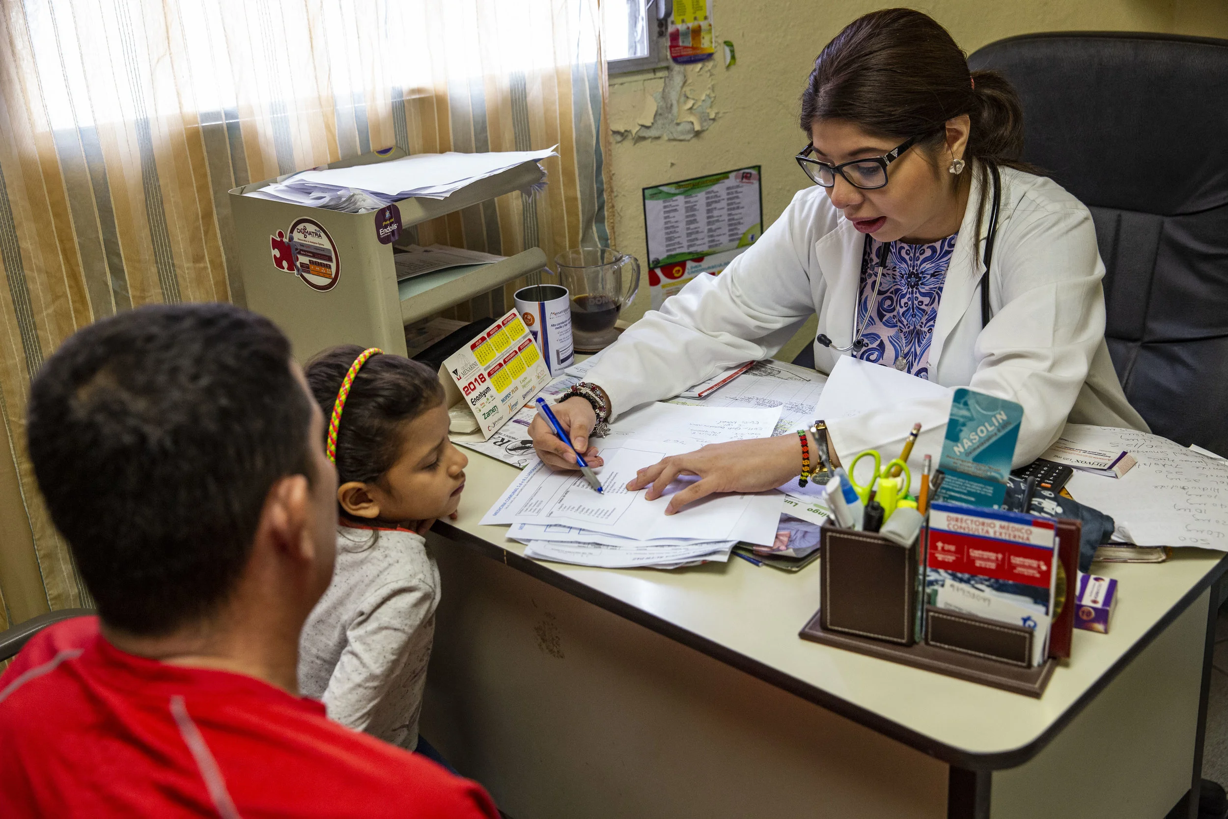 Doctor Sara Diaz prescribe medicines and give informations to a father and his daughter during a check-up at the Ruth Paz clinic in Bogràn, a pretty dangerous neighborohood in San Pedro Sula, Honduras.