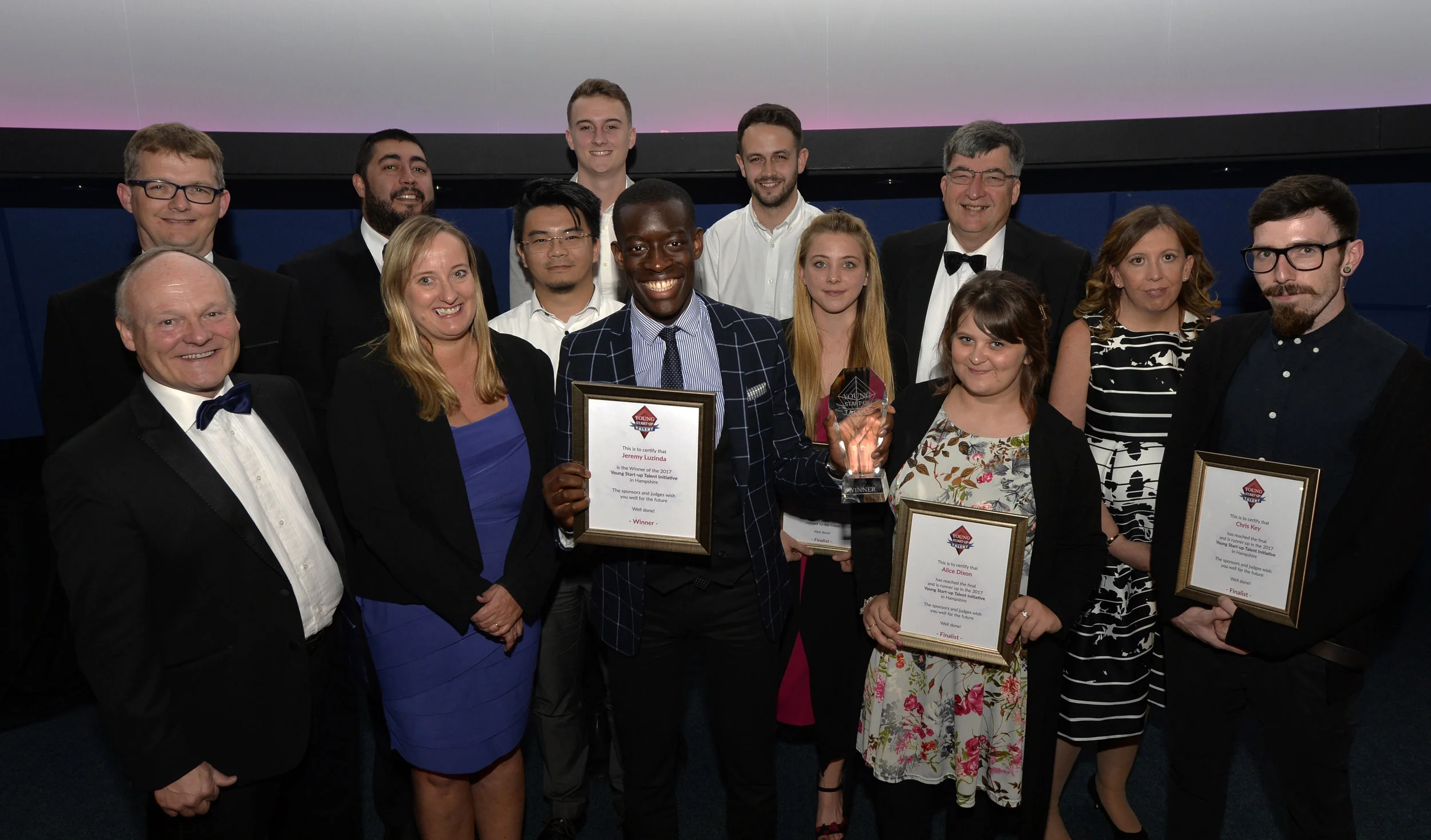 Judges and finalists on stage at Winchester Science & Planetarium [Left to right - Royston Smith MP, Paul Stacey, Mat Turner, Lorraine Nugent, Ming Wu, Jonathan Tellyn, Jeremy Mutebi, Adam Stannard, Natasha Tiffin, Chris Allington, Alice Dixon, Cheryl Gourlay and Chis key.
