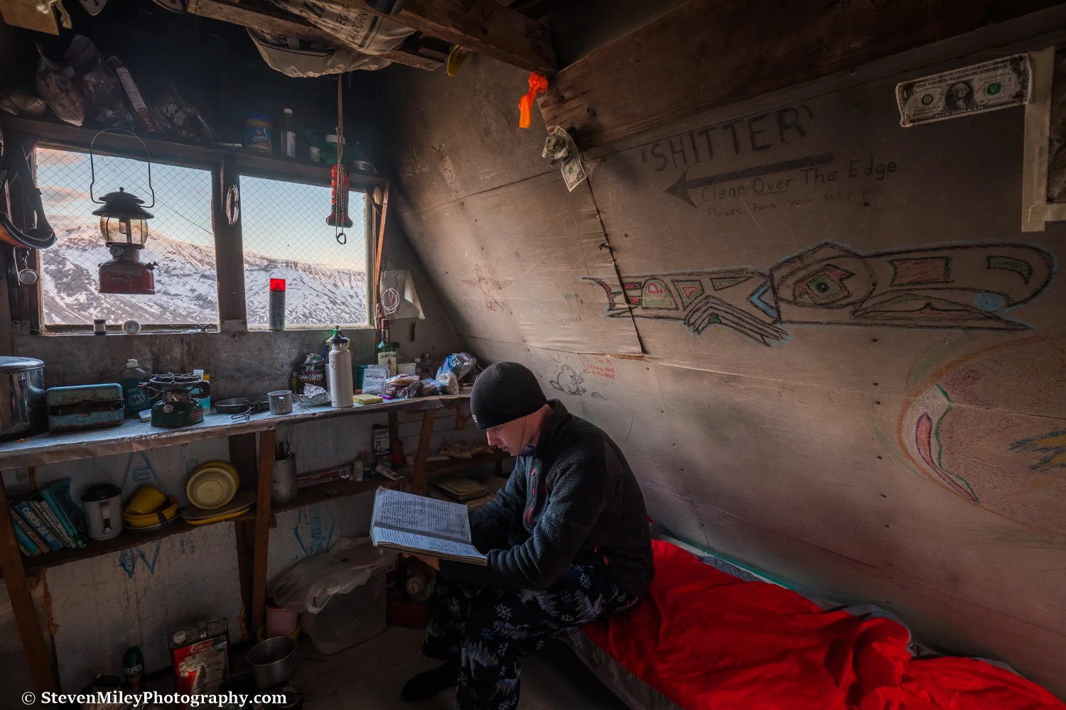 Reading the logbook. The hut is well-stocked with fuel, cooking utensils, and other gear, but some (all) of the food could use tossing.