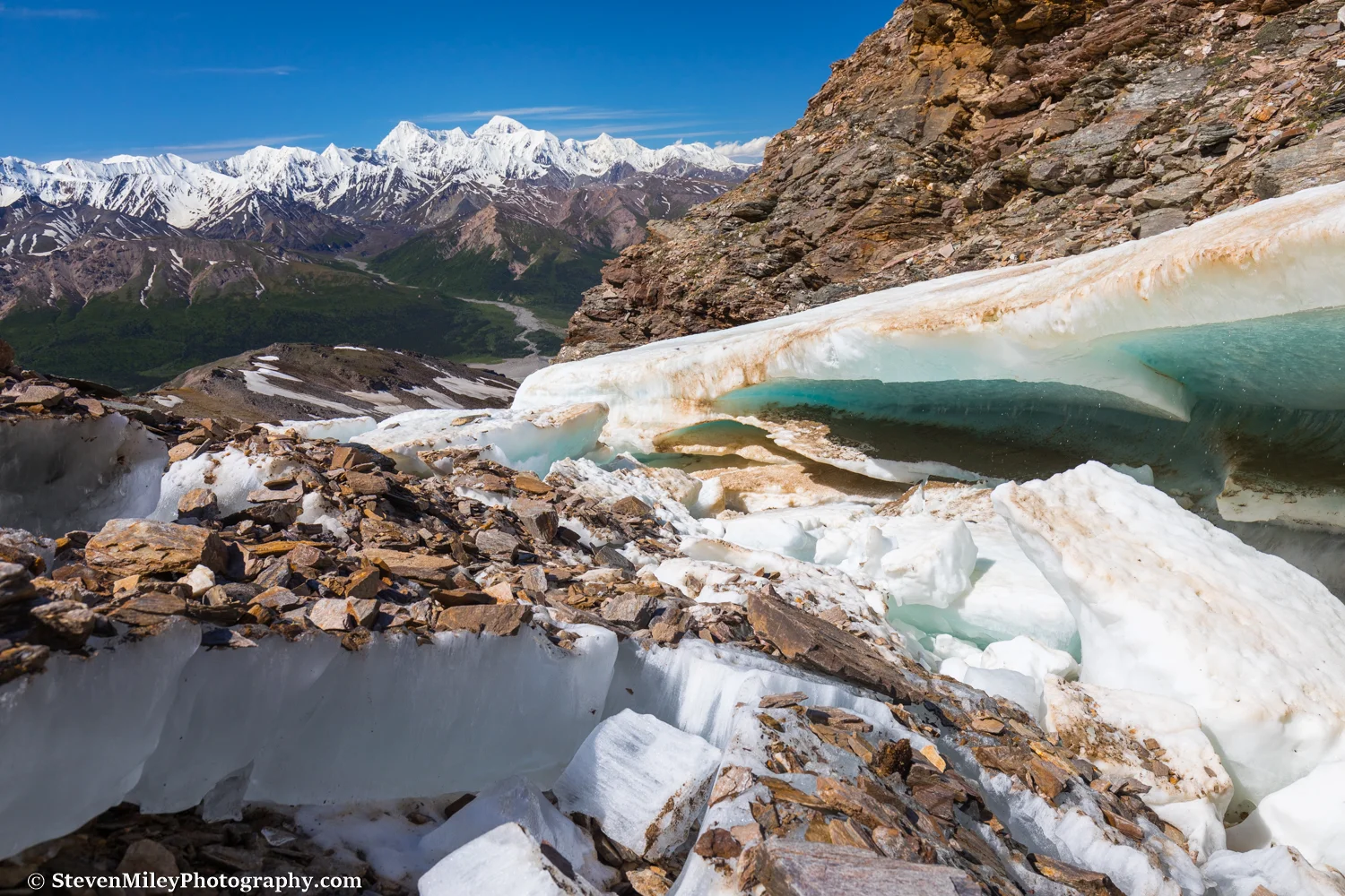 Snow-turned-to-ice melts along "Grizzly Creek" with the Hayes Range in the background.