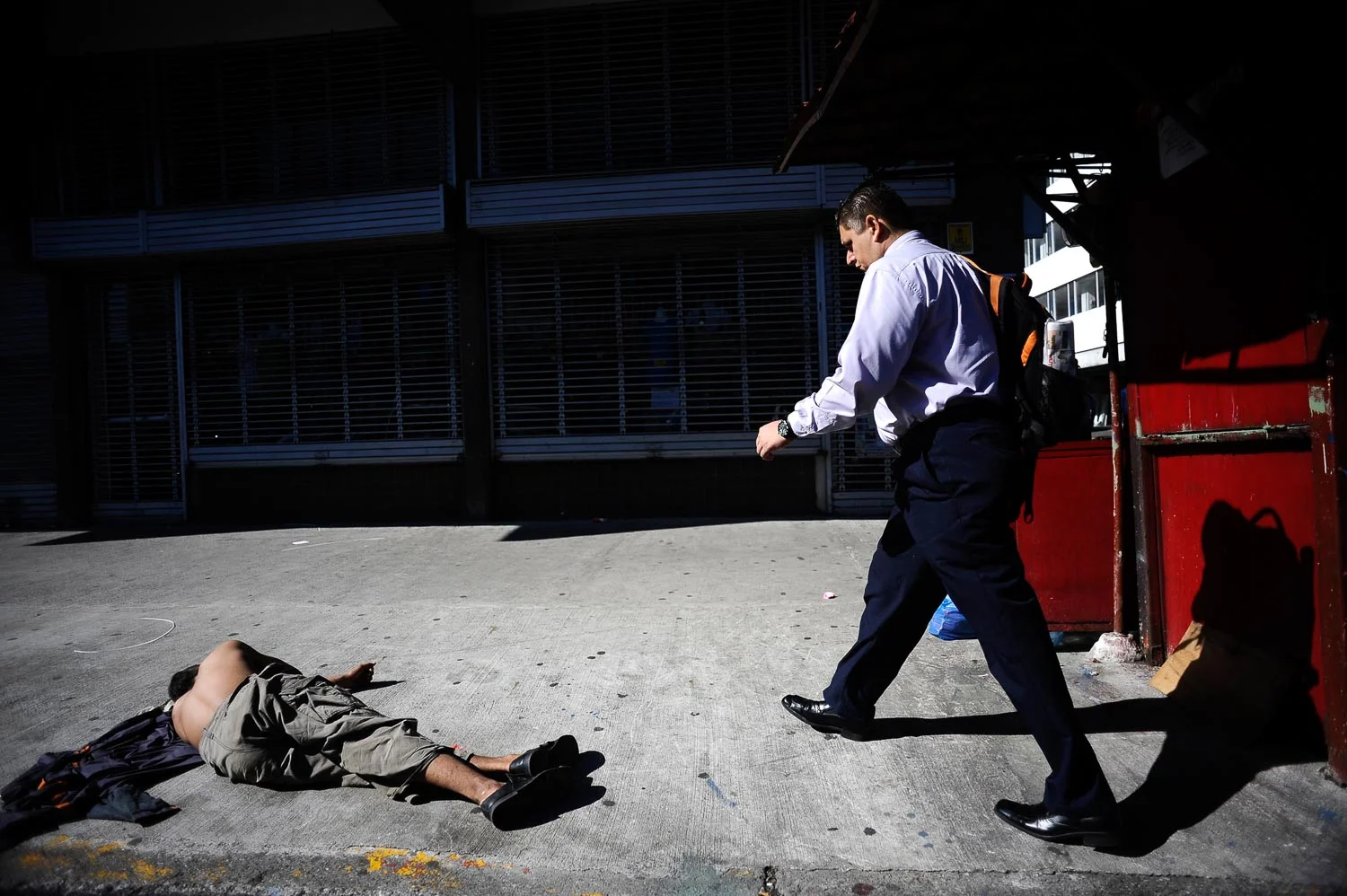  INEQUALITY UNDP REPORT - A business man walk on the side of a homeless crack addicted in the barrio of La Coca Cola - Francesco Vicenzi 