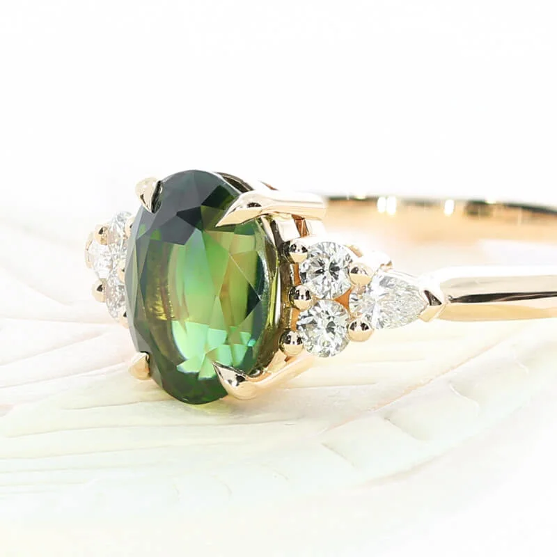 A bespoke engagement ring commission, featuring a teal oval sapphire and diamond set shoulders