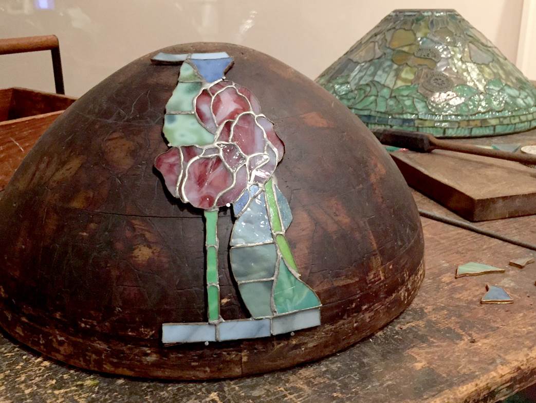 A work table from Tiffany Studios showing a lamp form with a shade under construction