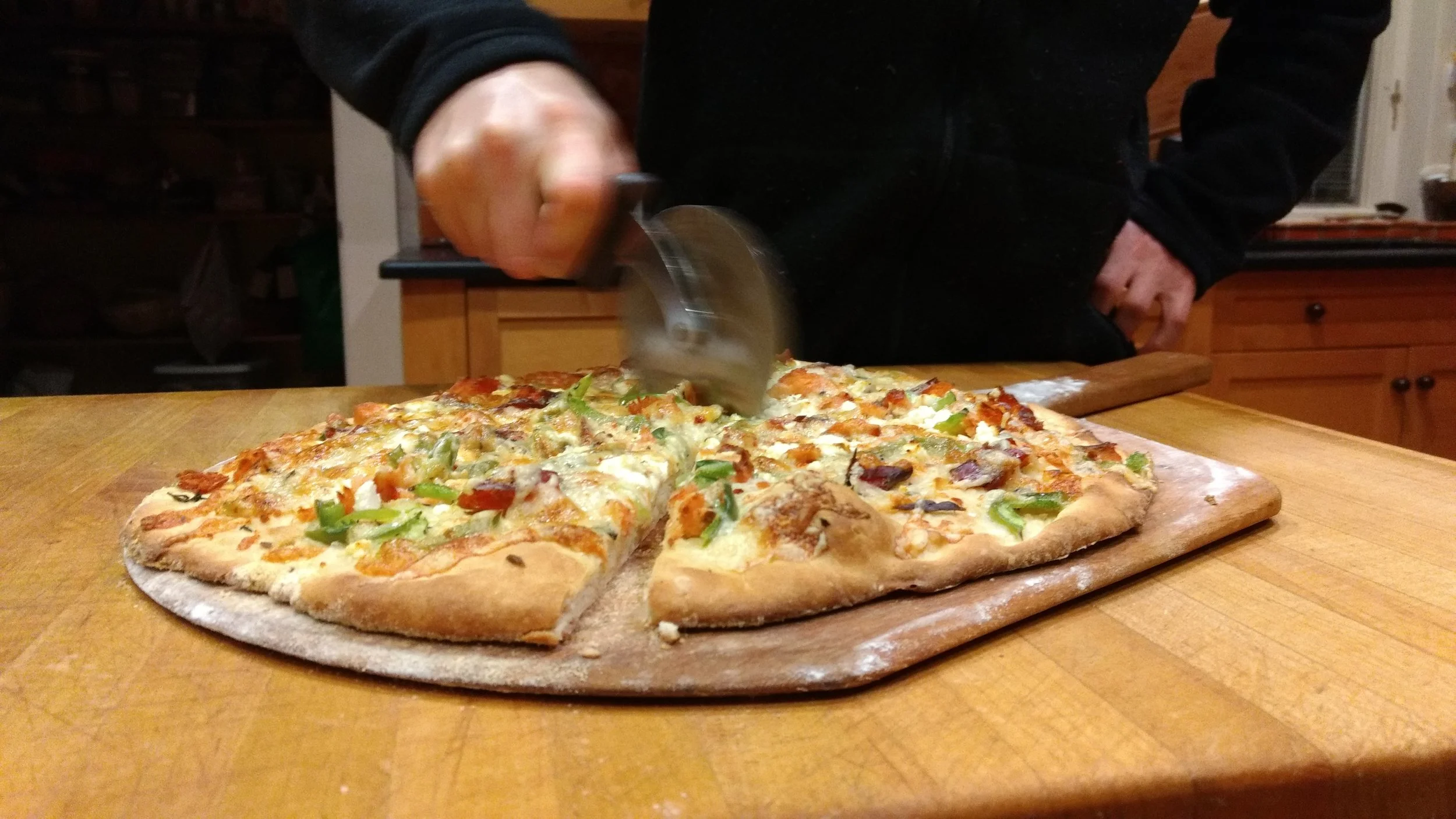 Here's how we do it: Preheat the oven to 450 degrees with a baking stone inside. Dough : You can use any dough you like. When we're fishing, time is often at a premium, so we love 5 minute pizza dough . Toppings: The most important ingredients are creativity, love, and good friends to share it with. We also like to drizzle the crust with olive oil and sprinkle with herbs (sage is a favorite) and a pinch of good salt on top. Then we add flaked smoked salmon, bell peppers, and a variety of cheese including feta, swiss, and white cheddar with roasted red pepper. Bake: When your oven is hot, sprinkle cornmeal on the pizza stone and slide the pizza on to the stone using a pizza peel. Bake for 15 minutes or so (individual ovens will vary). 
