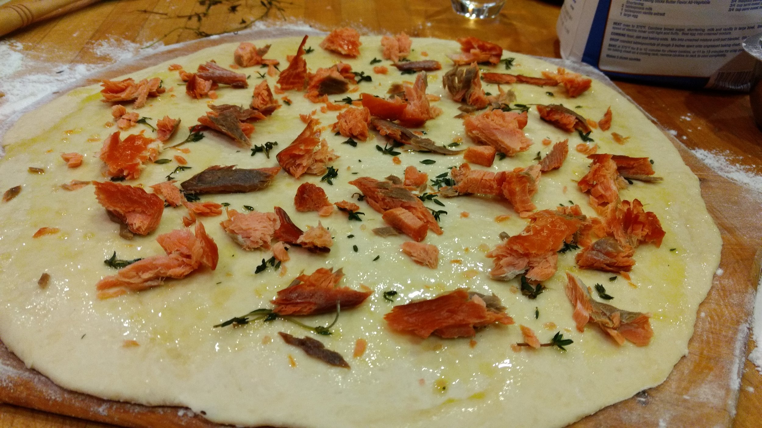 We love pizza made without red sauce. Here we start with olive oil, a little sage, and smoked salmon!