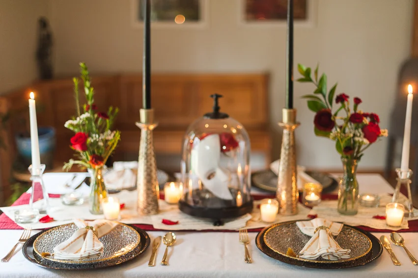 Thrifted vases, sheet music, red table runner. Plates, napkins, clear candlesticks are clearance HomeGoods, tall gold candlesticks are clearance Anthropologie, and the napkin rings and cloche are Halloween clearance from Target.