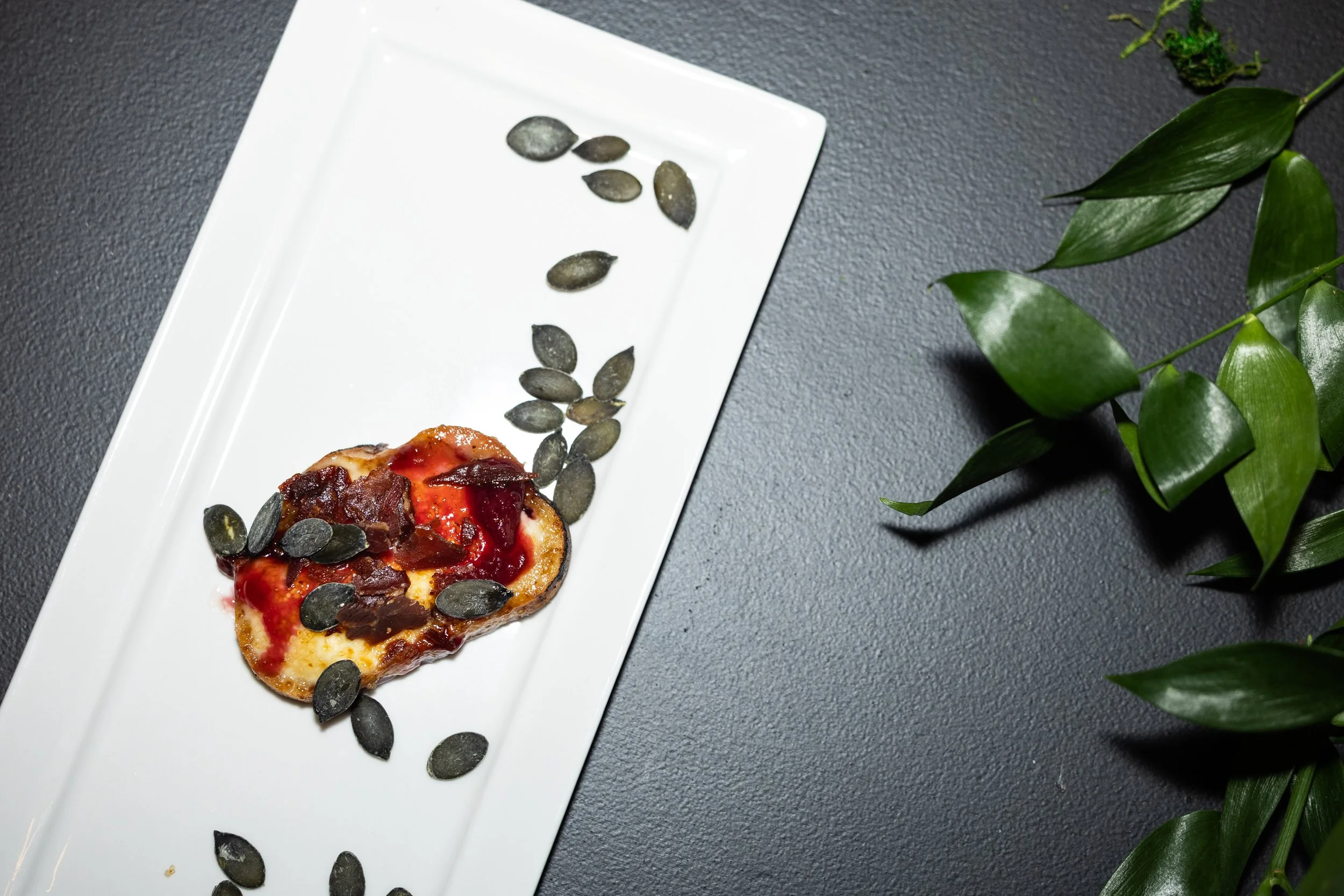 Bruleed cheese with ham and lingonberry jam, on a white plate on a black table