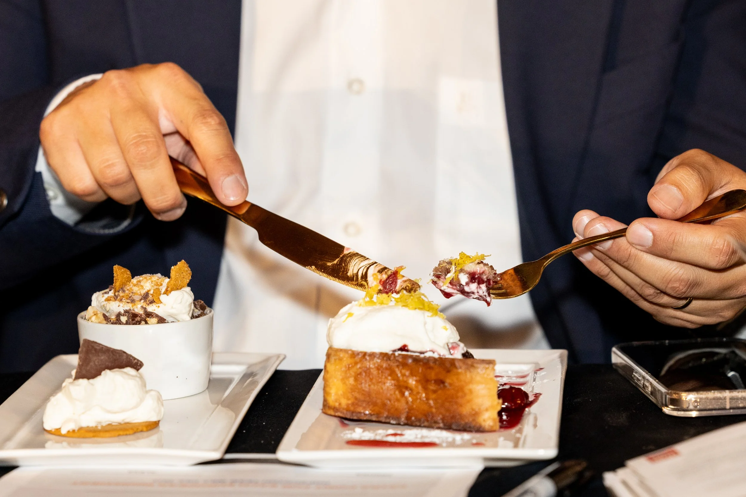 a man holding a gold fork and knife cuts into two decadent chocolate desserts at the Taste Europe challenge