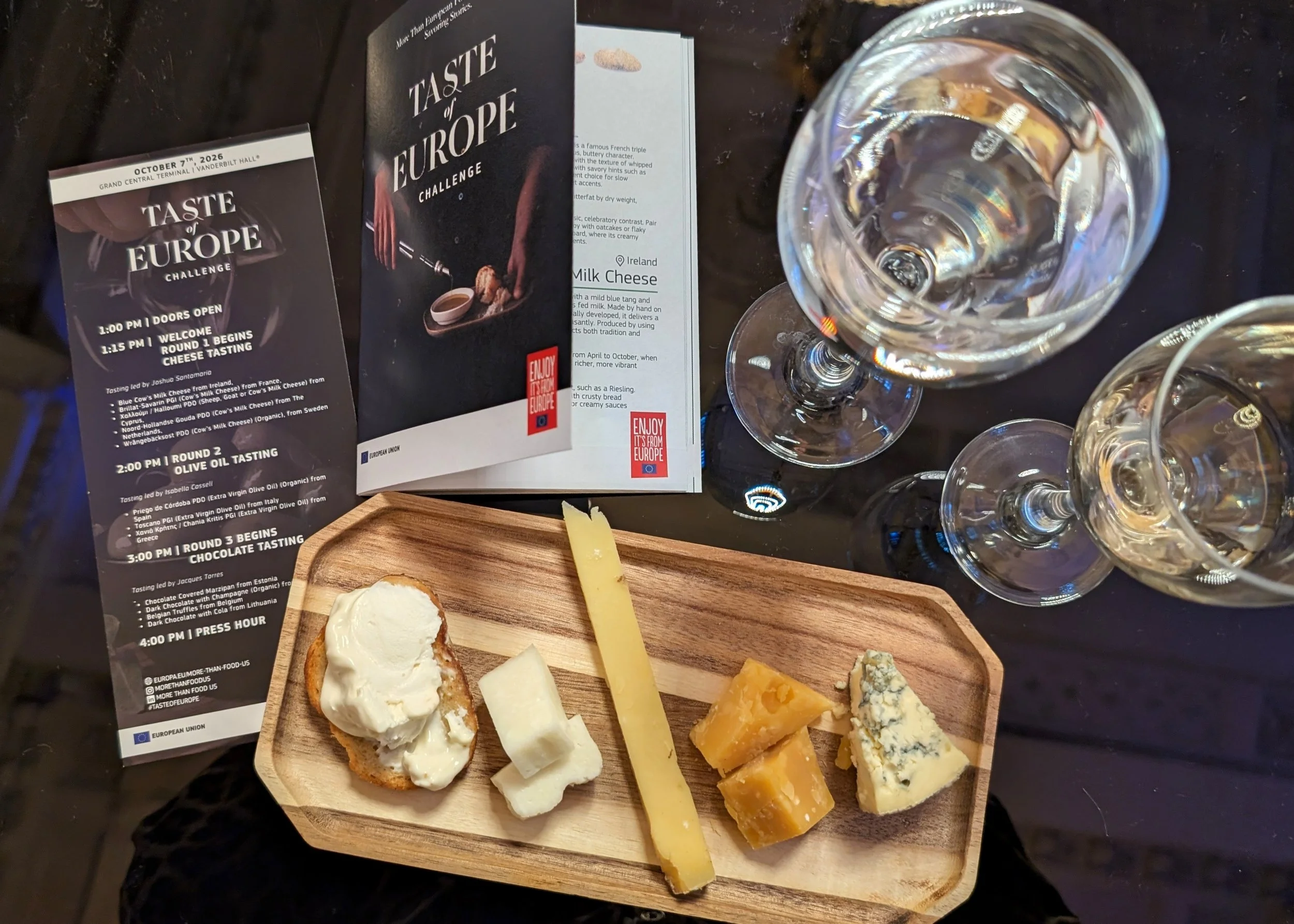 a flight of 5 european cheese on a bamboo board, black table