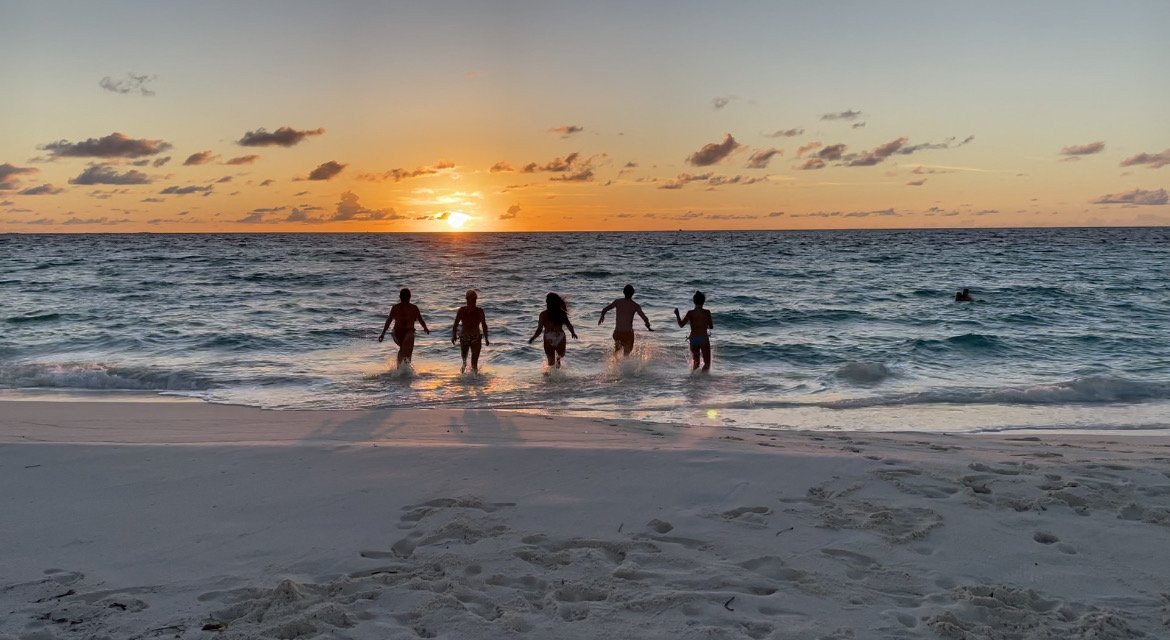 extraordinary escapes team running into the water at sunset