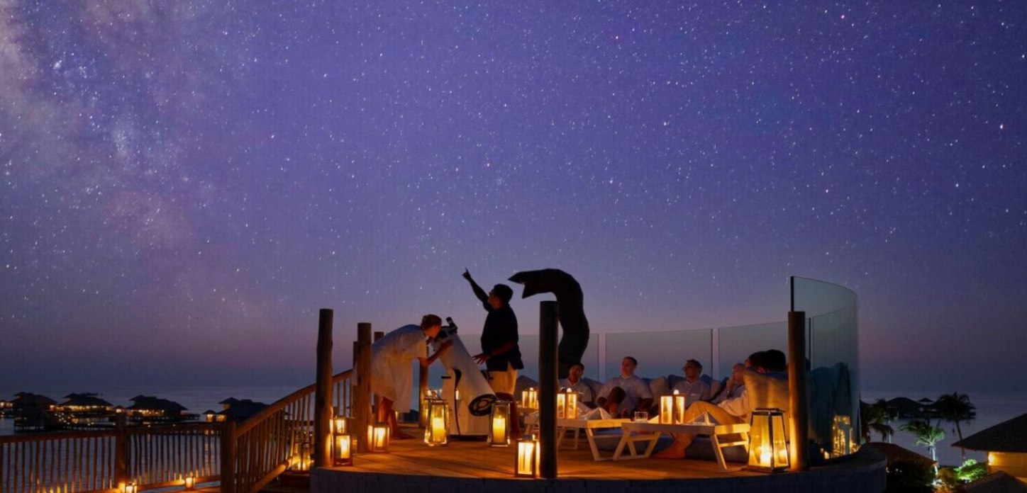 PEOPLE STARGAZING ON A ROOF TOP IN THE MALDIVES