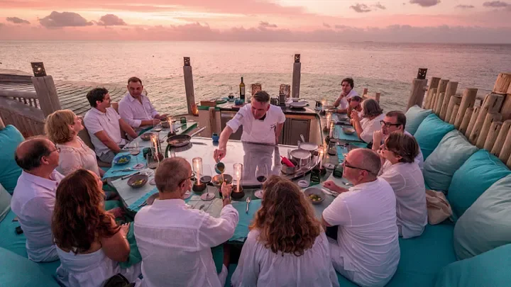 Group of people dining at sunset overwater