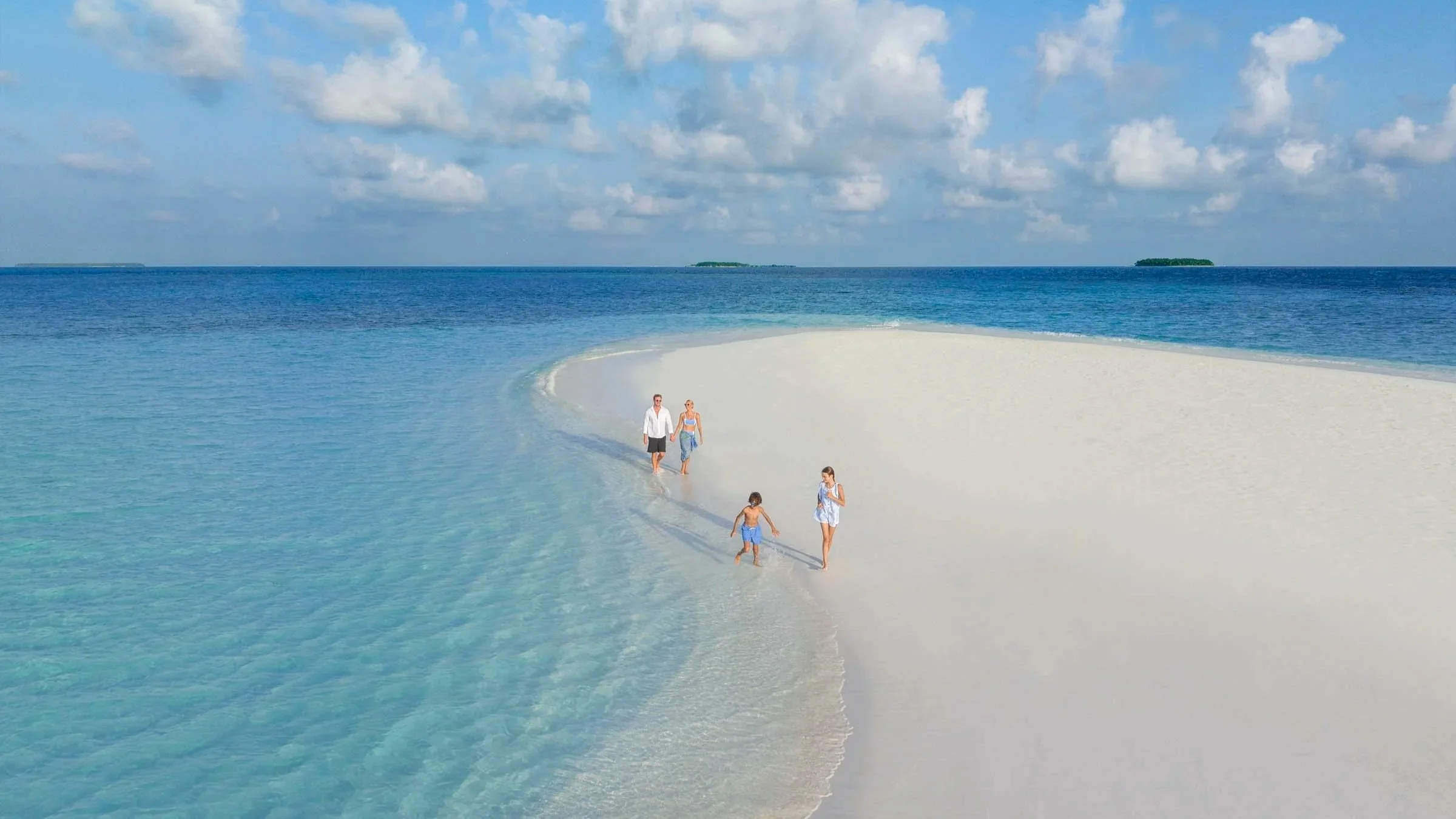 Family walking on white sand beach