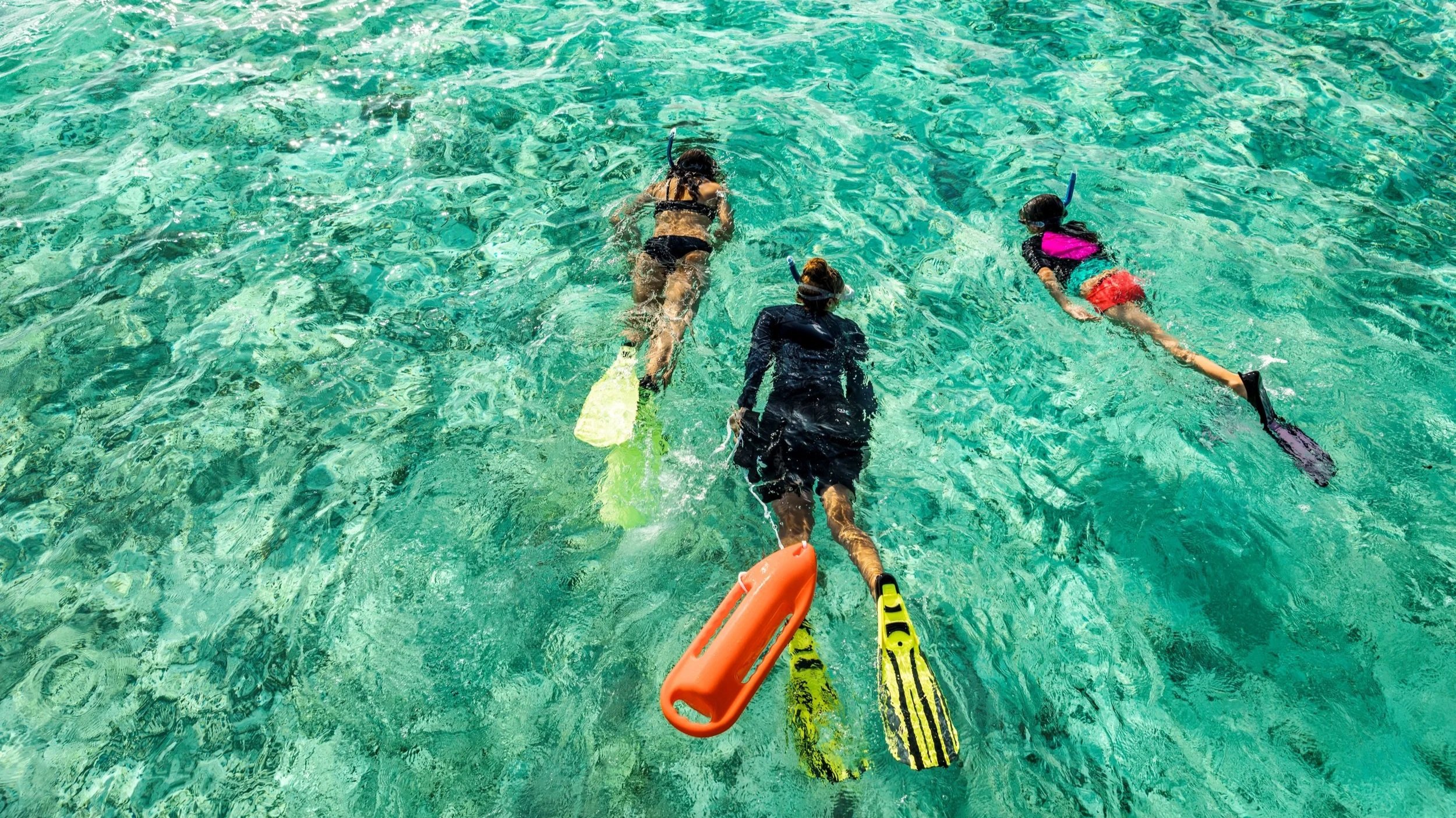 Lady with two children snorkeling in aqua water