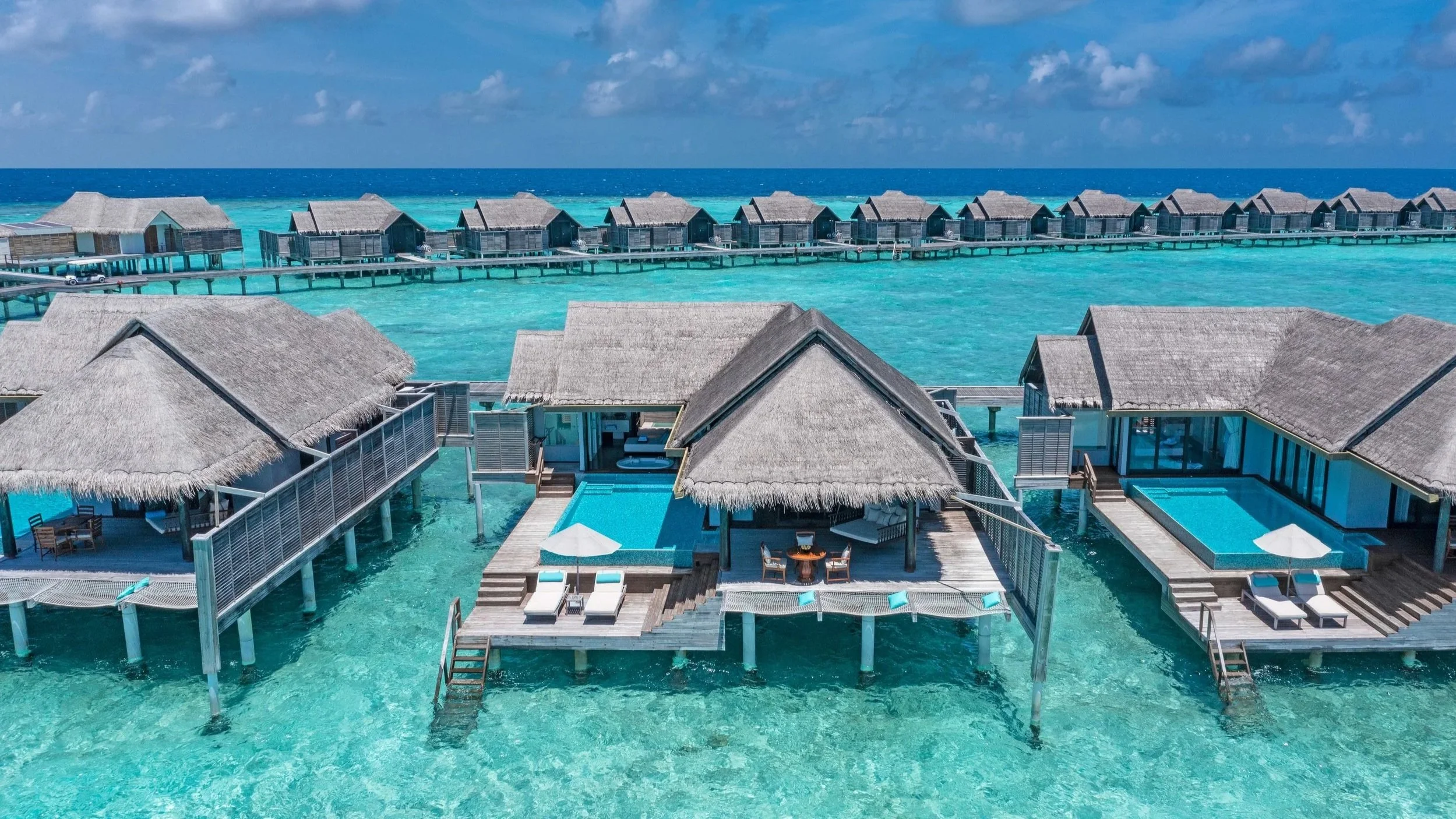 An overwater villa deck with pool, deck chairs and over water nets, showing swing as well