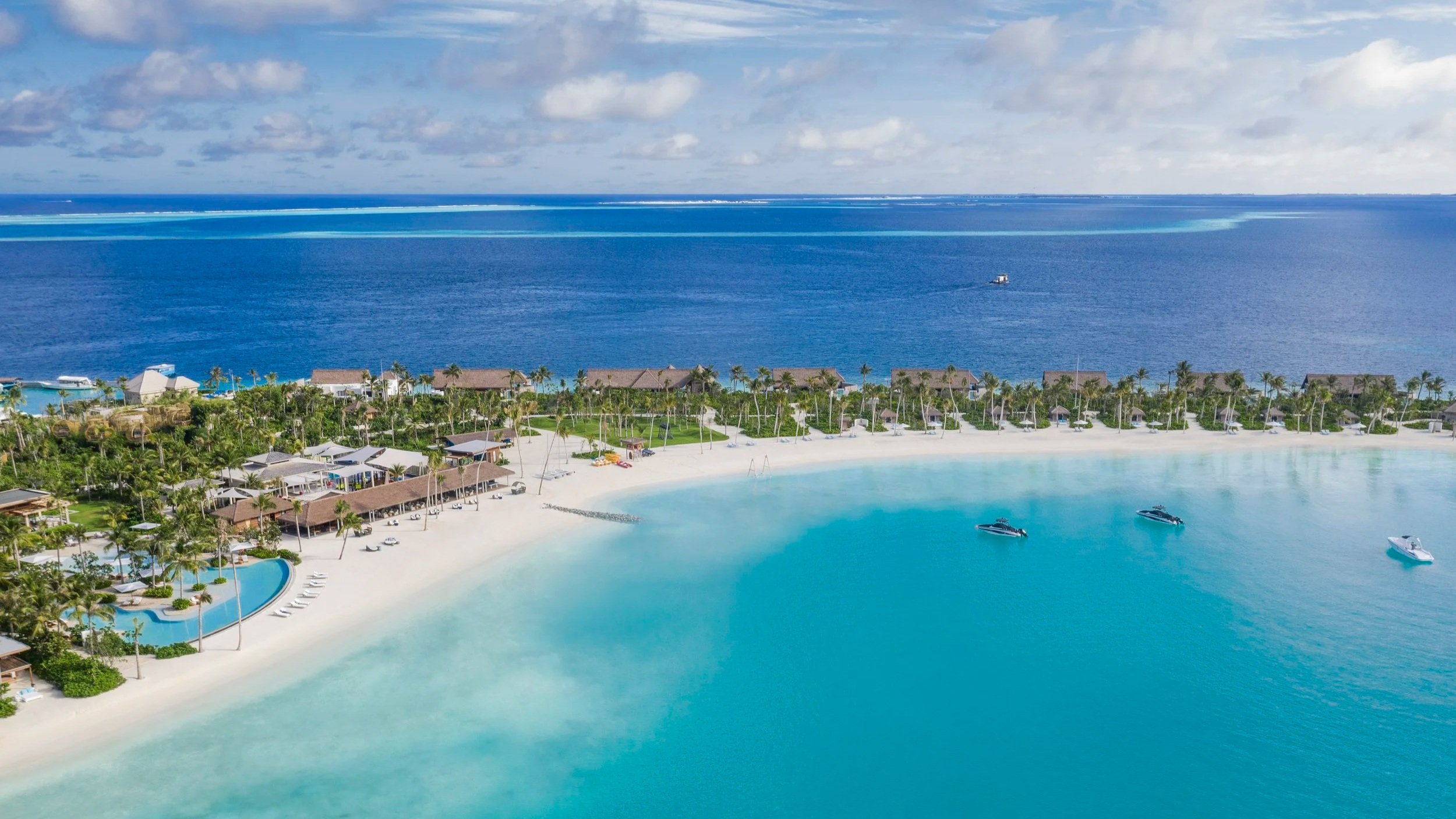 Aerial view of an island with beach club, villas and boats