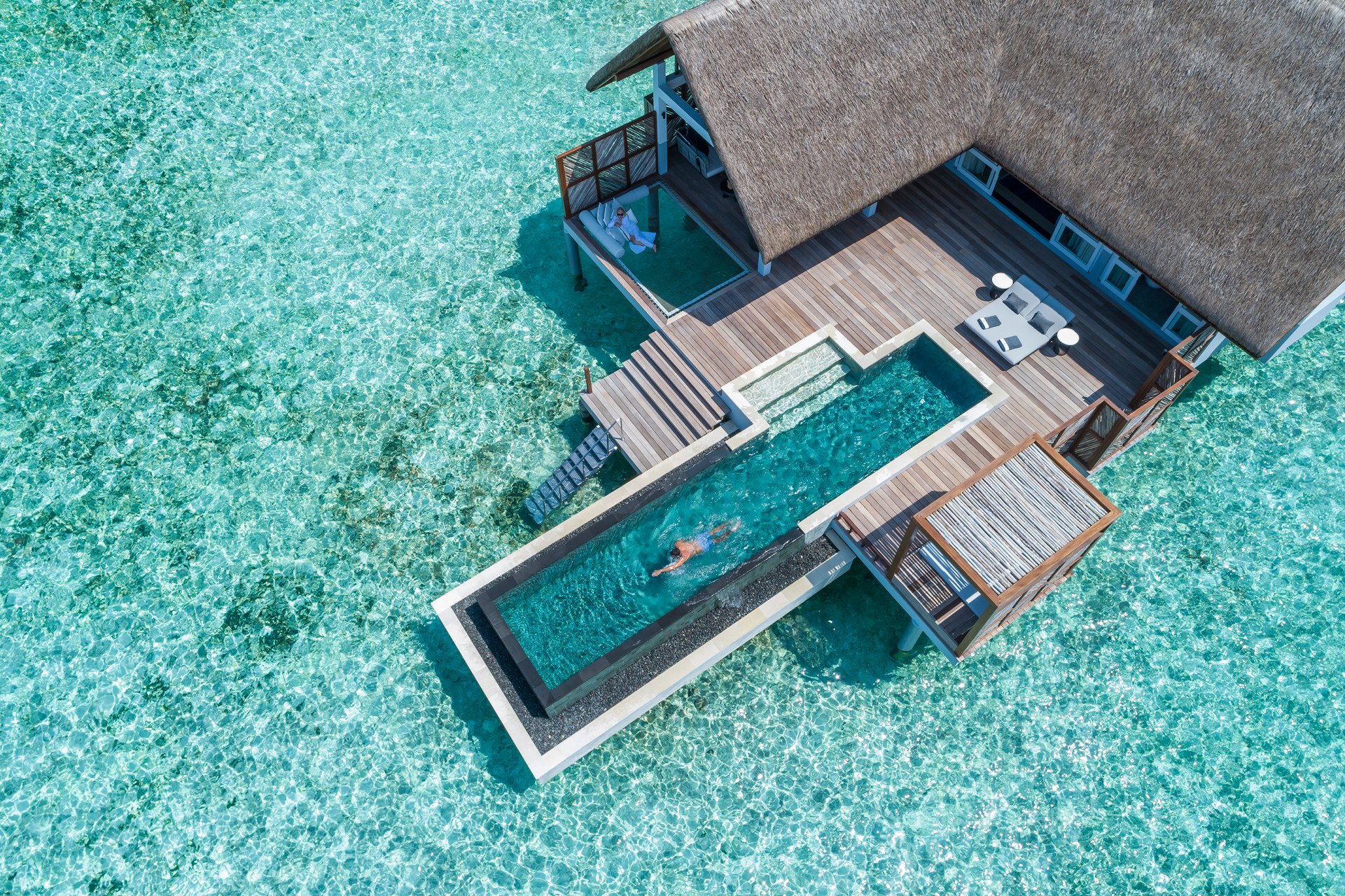 Aerial view of a water villa with person swimming in private pool