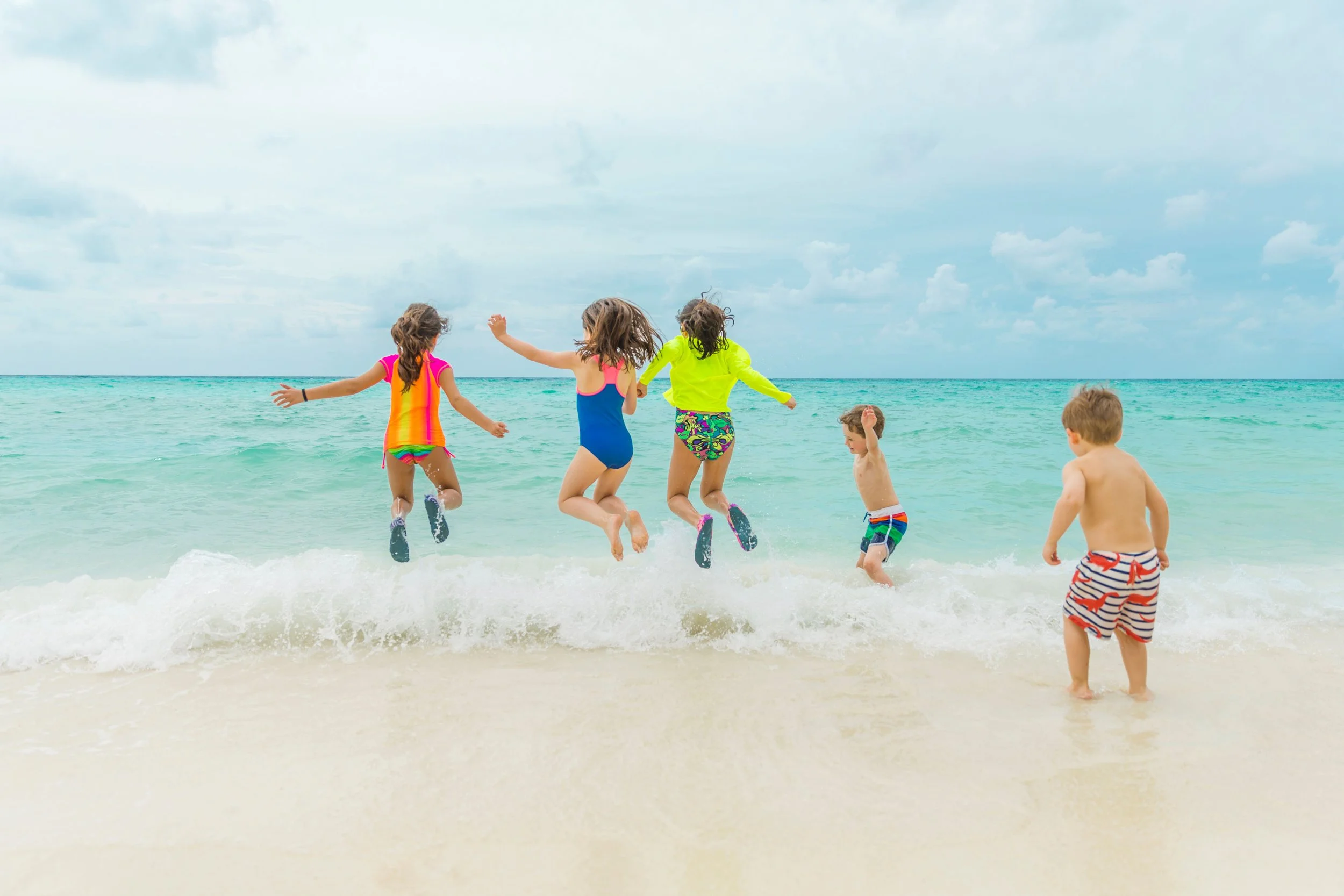 KIDS ON THE BEACH PLAYING IN THE WATER