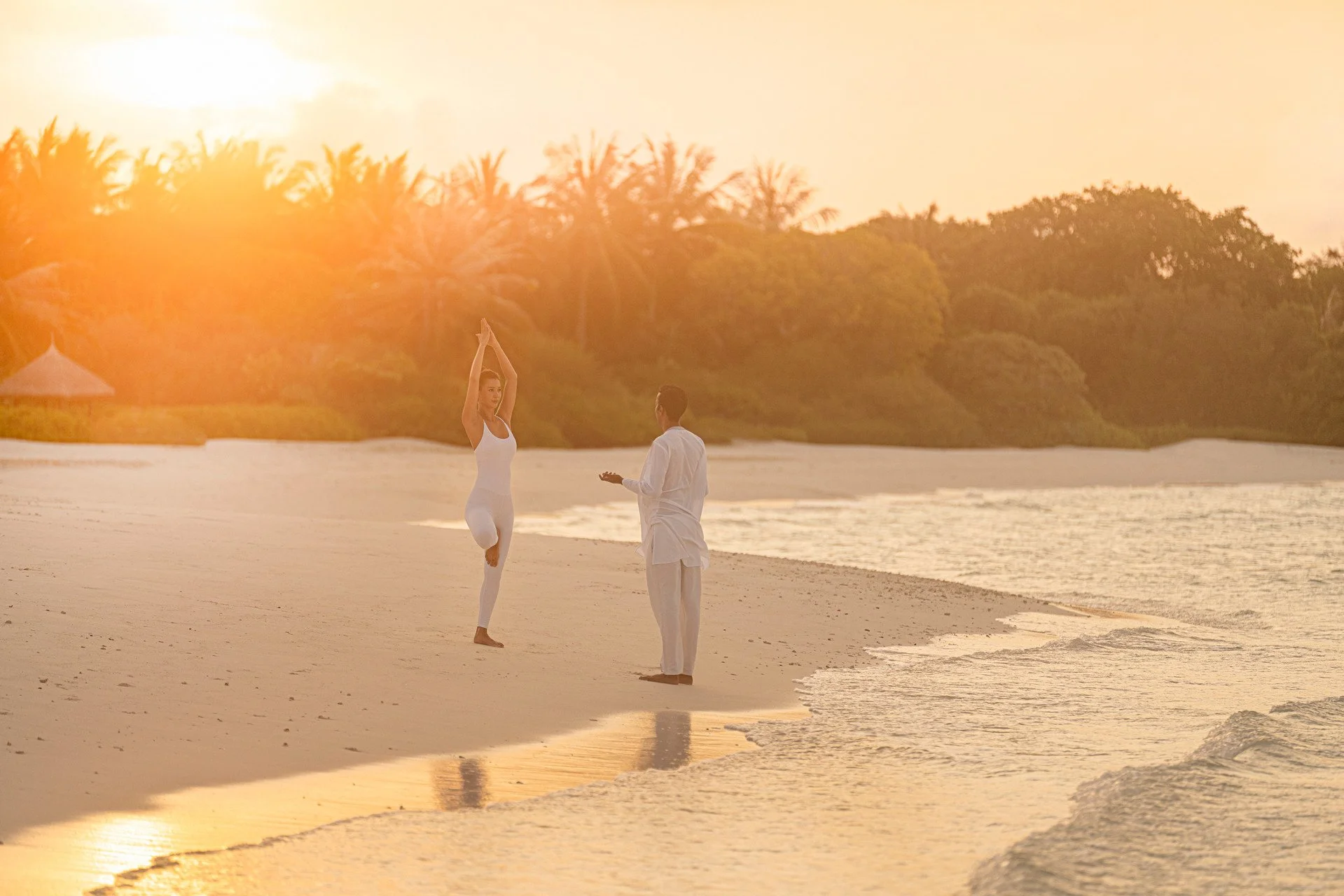 couple doing yoga at sunrise on the beach