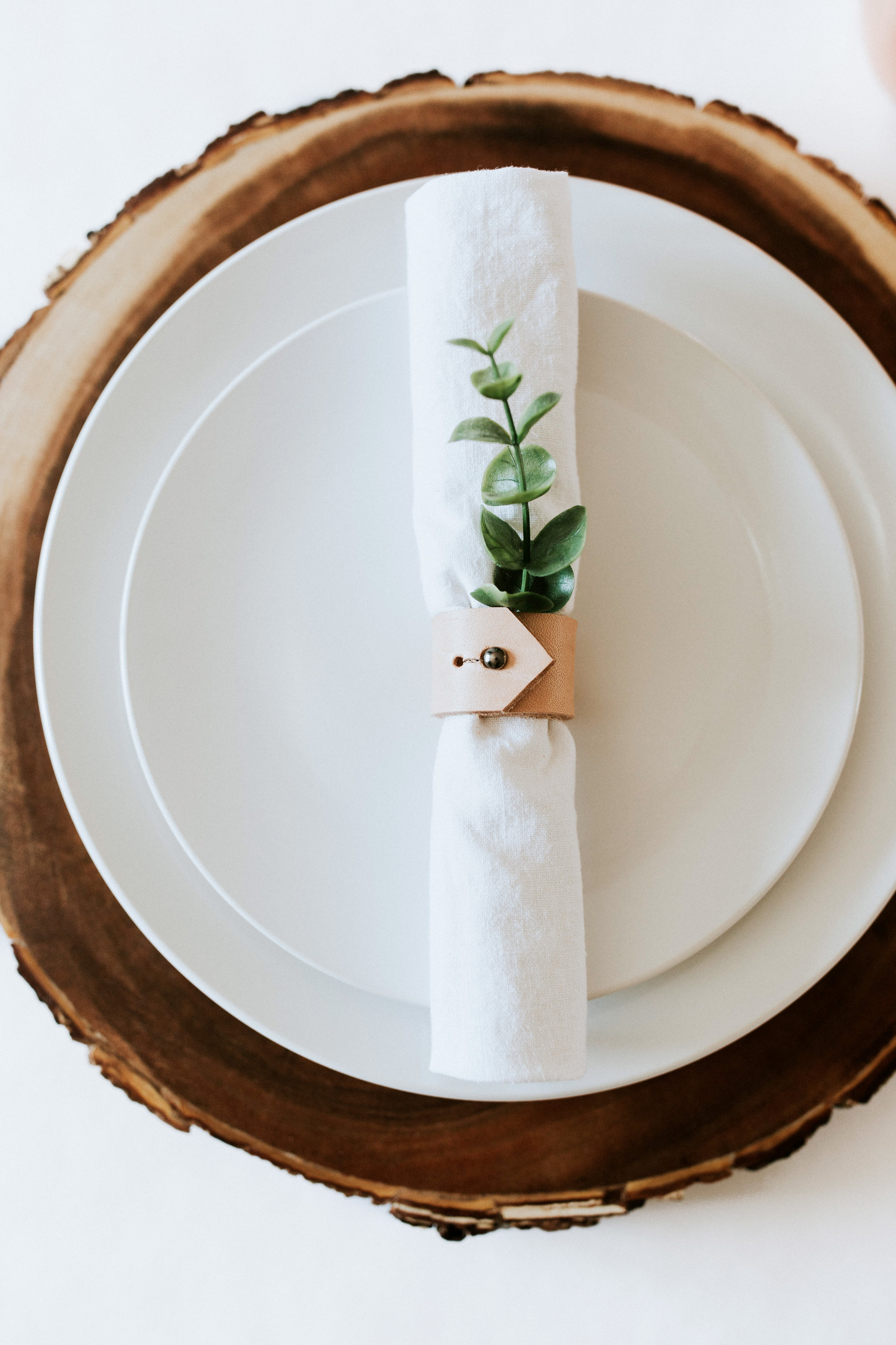 How to create / DIY a natural minimal table setting - wood charger, white plates, white napkin, leather napkin rings, greenery