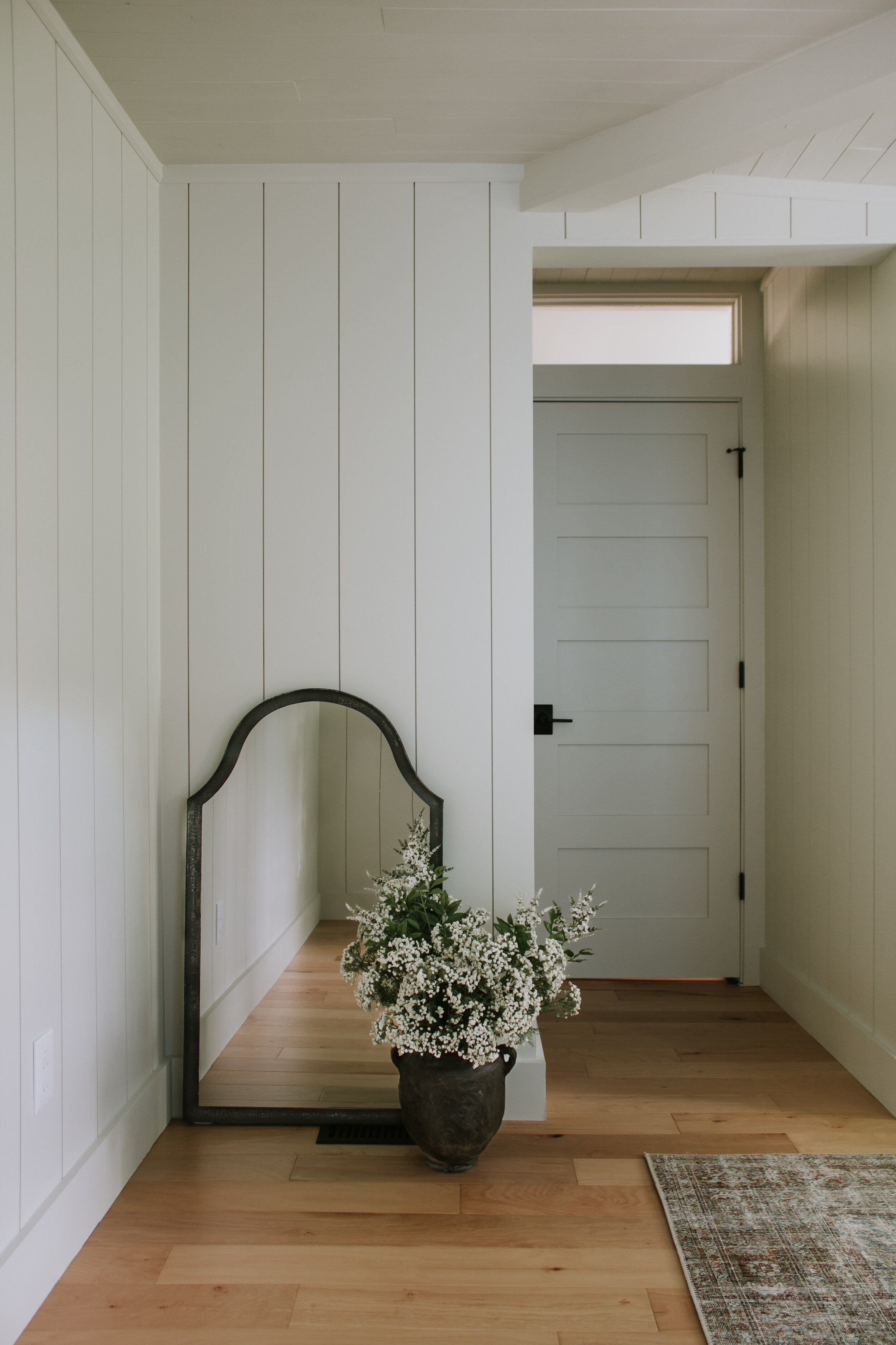 A peek at the paint color we chose for our primary bedroom makeover. A putty warm white neutral for the walls. Vertical Shiplap, nickel gap planks on the walls and wood slatted ceilings create a modernized cabin bedroom retreat. | Nadine Stay