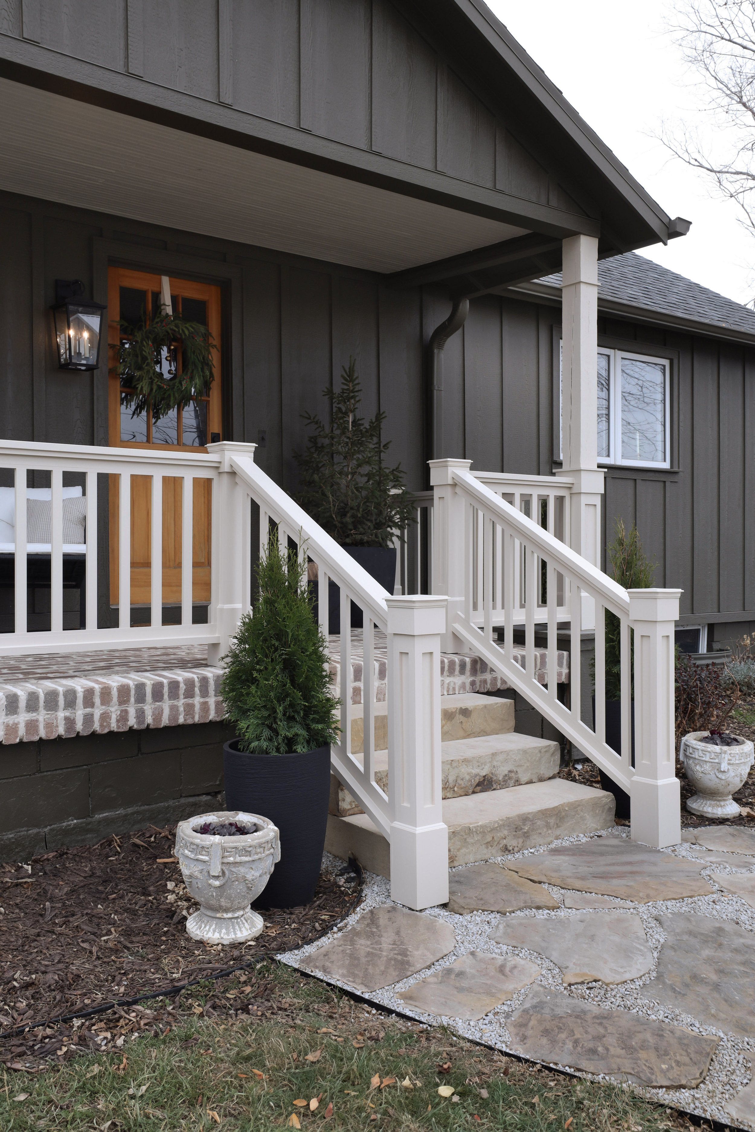 Porch before and after by Nadine Stay | Green exterior paint color. DIY porch brick floor. DIY flagstone path. DIY custom porch railing. Beige paint color for exterior. A craftsman porch railing. Box trim on porch railing posts.
