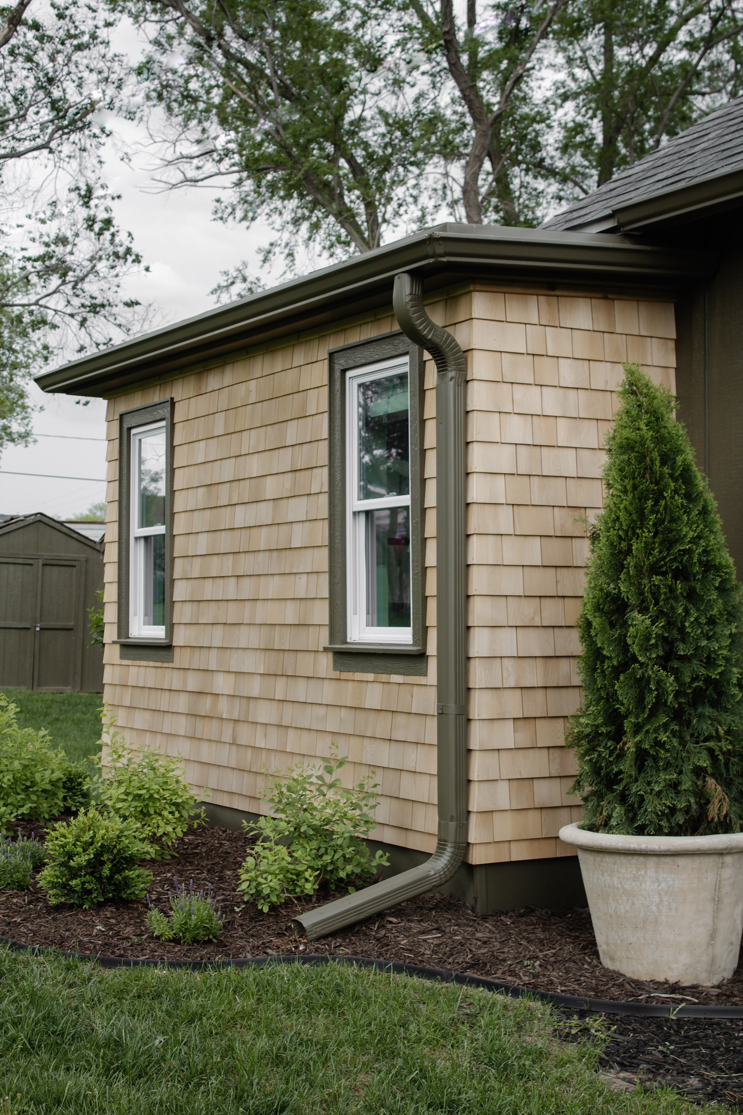 Cedar shingle exterior siding reveal. How we remodeled our exterior from rusty siding to cedar shakes. Hunter green and cedar shingle exterior transformation. English garden landscaping inspiration. | Nadine Stay