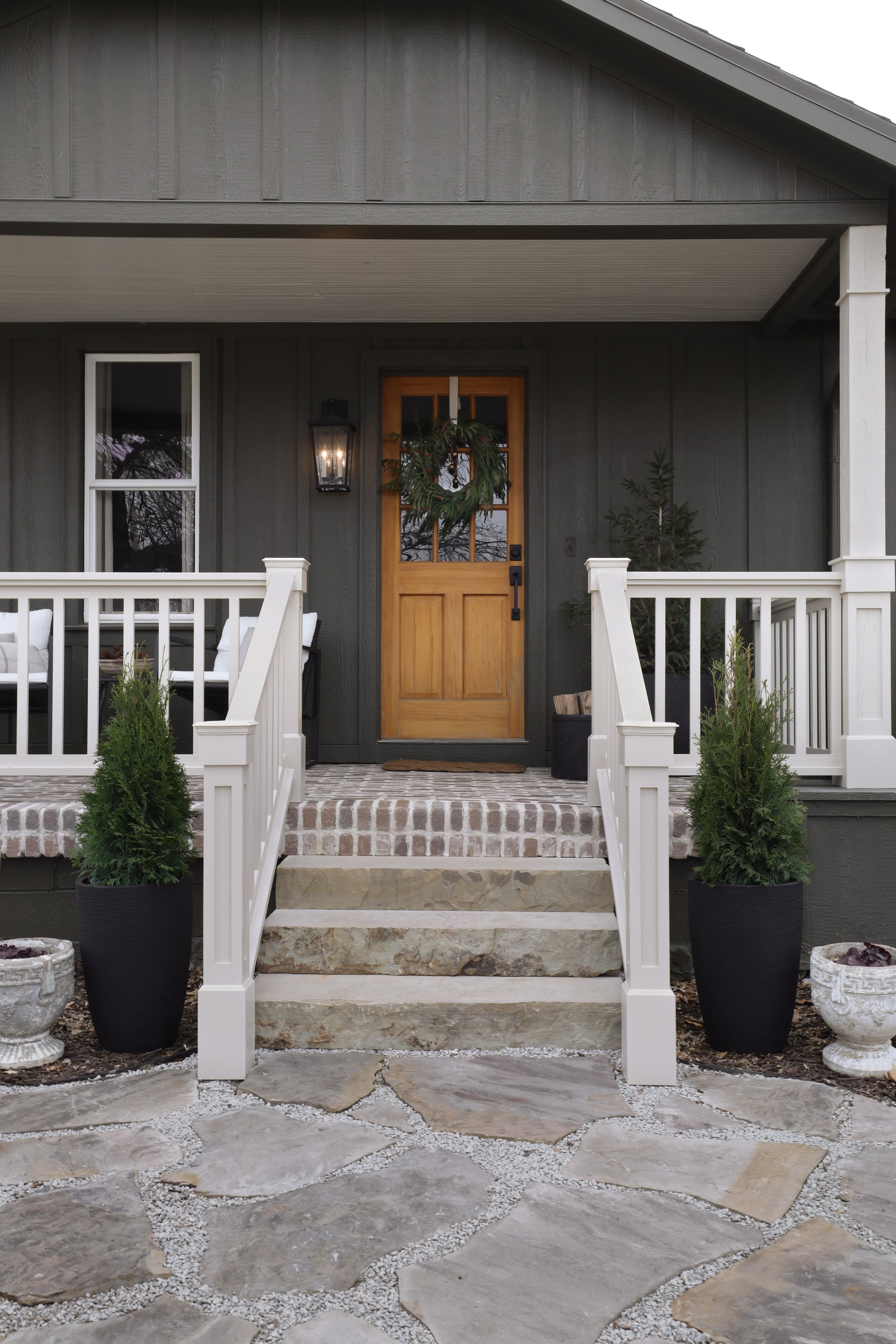 Porch before and after by Nadine Stay | Green exterior paint color. DIY porch brick floor. DIY flagstone path. DIY custom porch railing. Beige paint color for exterior. A craftsman porch railing. Box trim on porch railing posts.