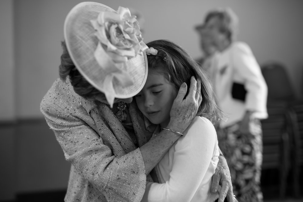 Grandmother embraces her granddaughter flower girl at wedding