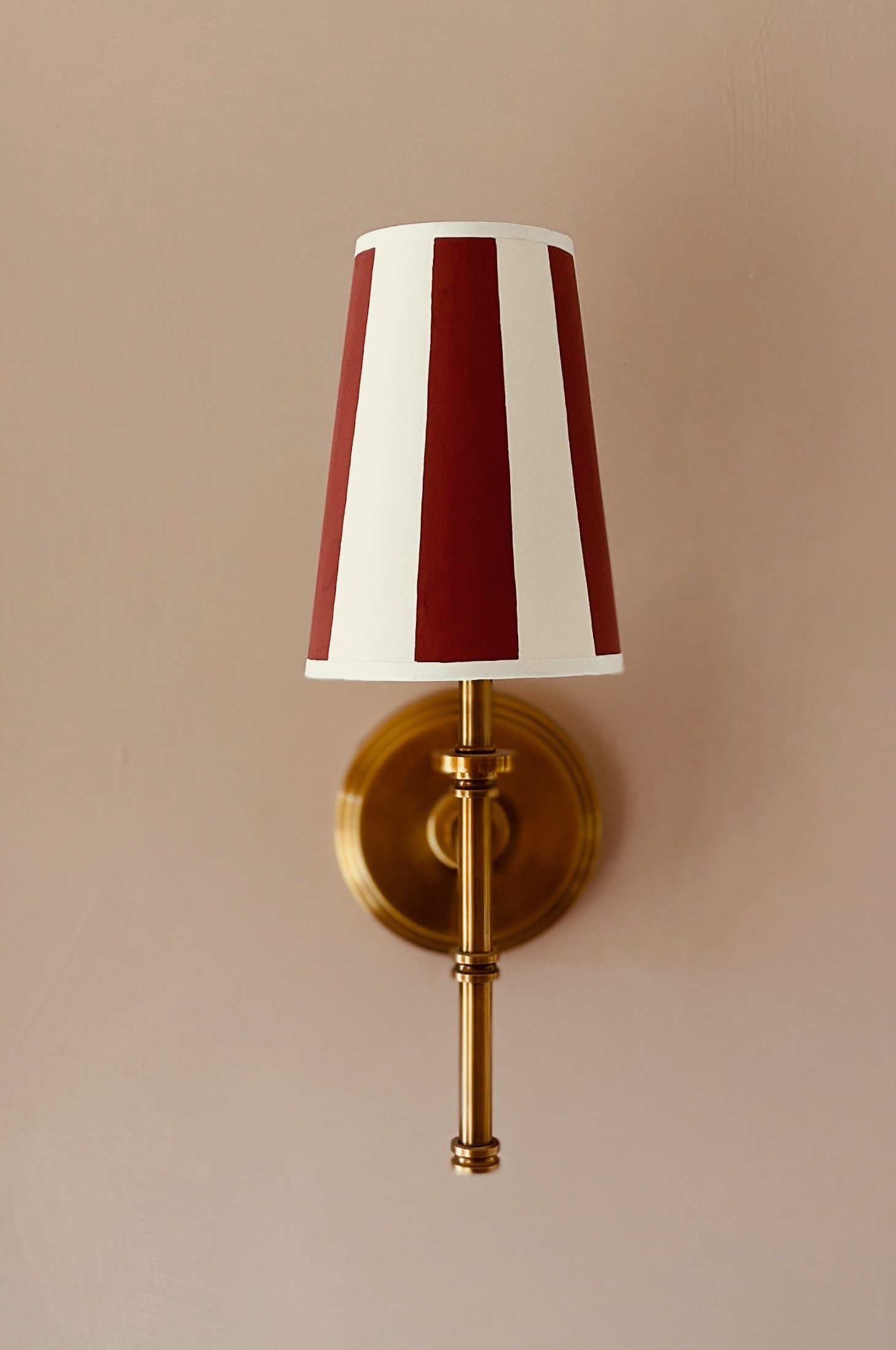 A small shade for a wall light with dark red stripes 