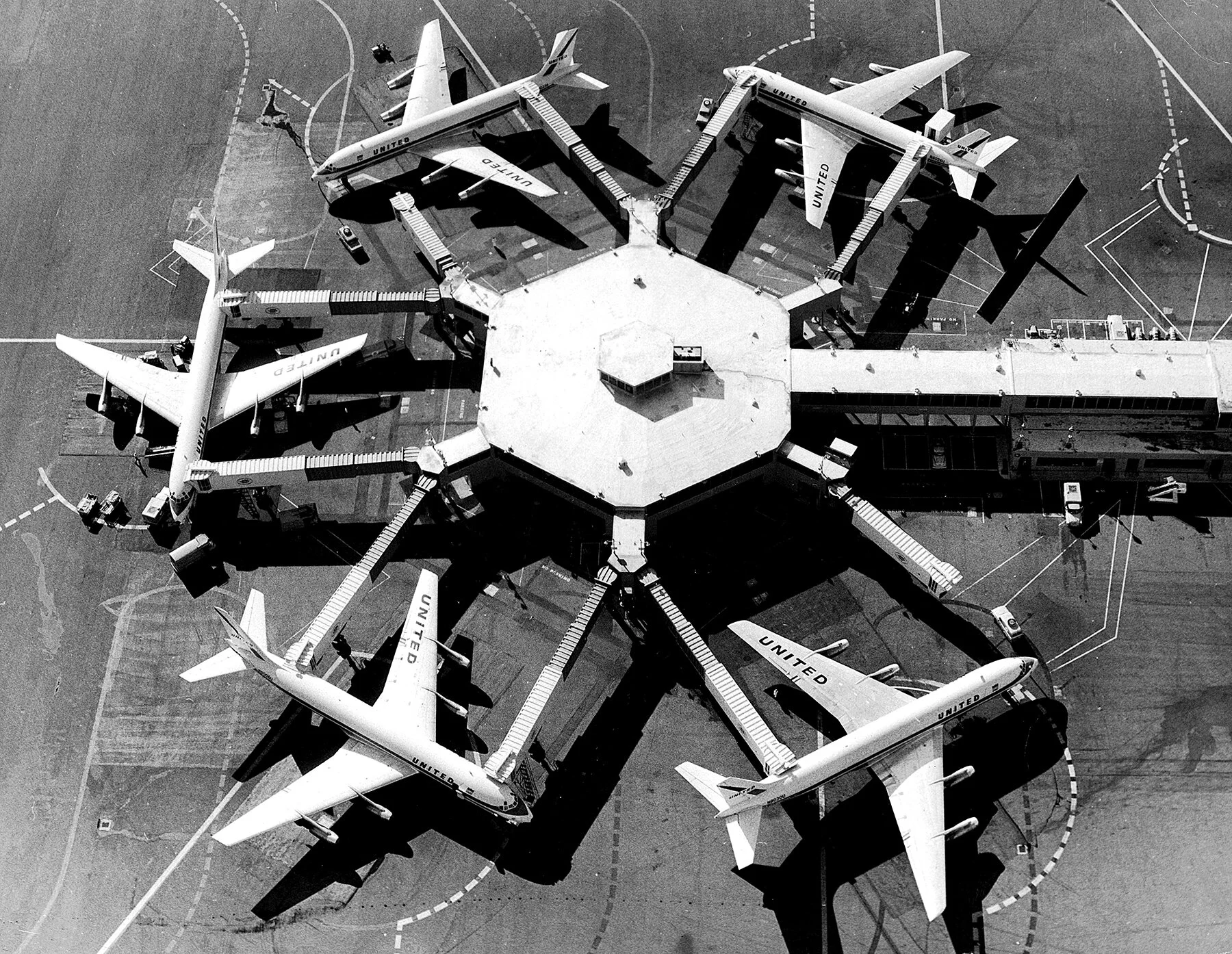 United Air Lines DC-8 jets parked at tandem aero-gangplank loading bridges, San Francisco International Airport, circa 1962.