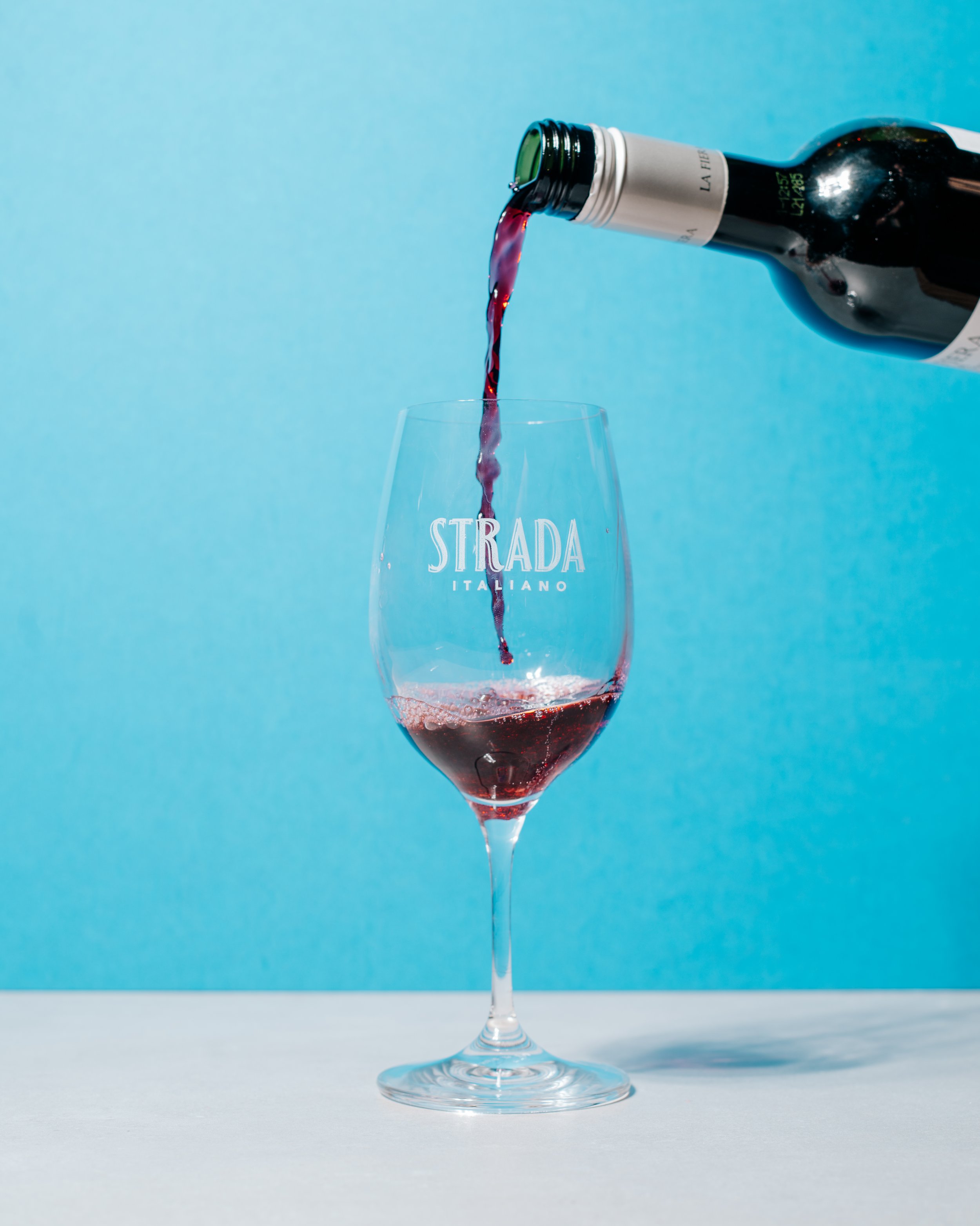 pouring wine into wine glass with Strada Italiano logo (Copy)