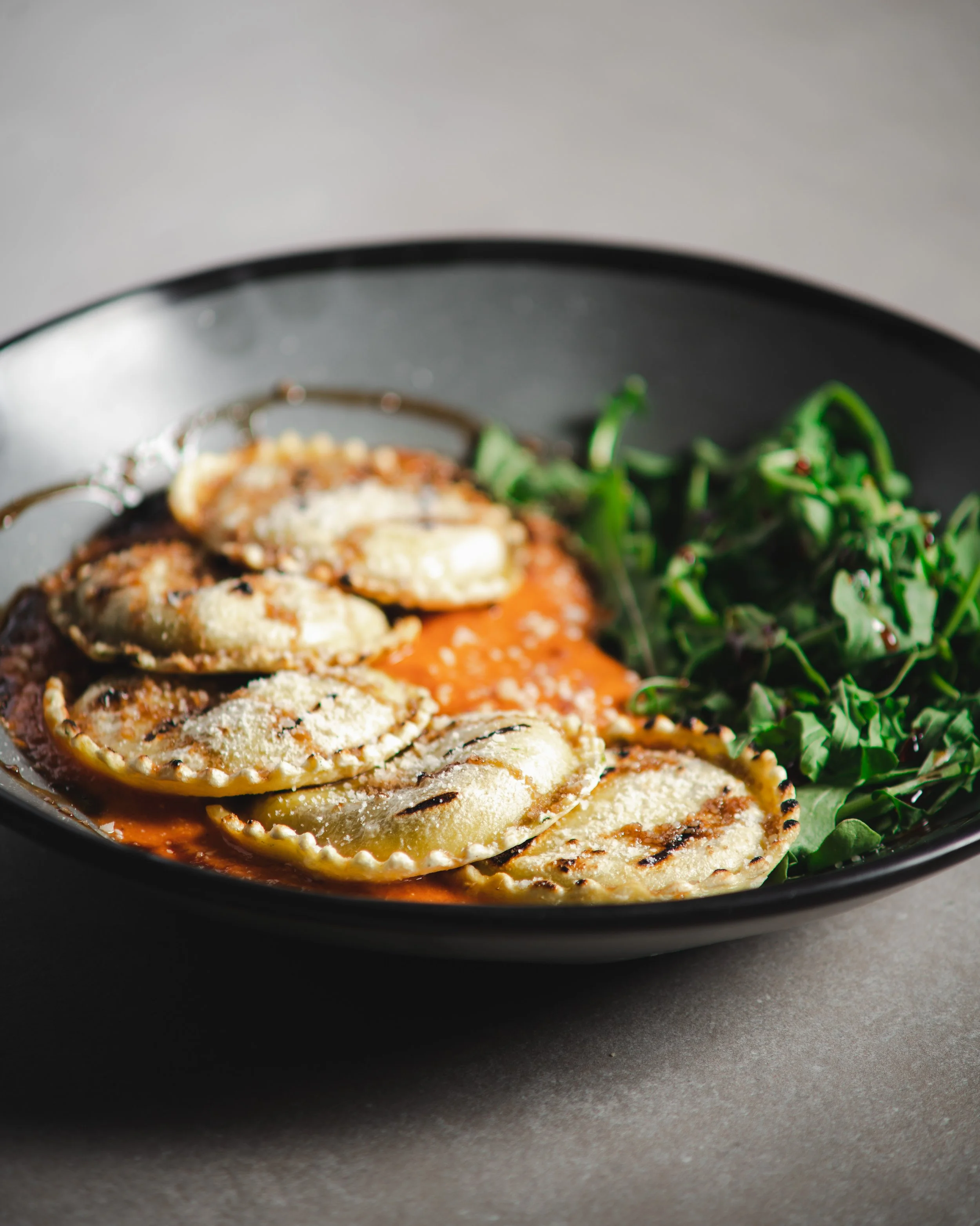 Ravioli and arugula with red sauce in a blue bowl (Copy)