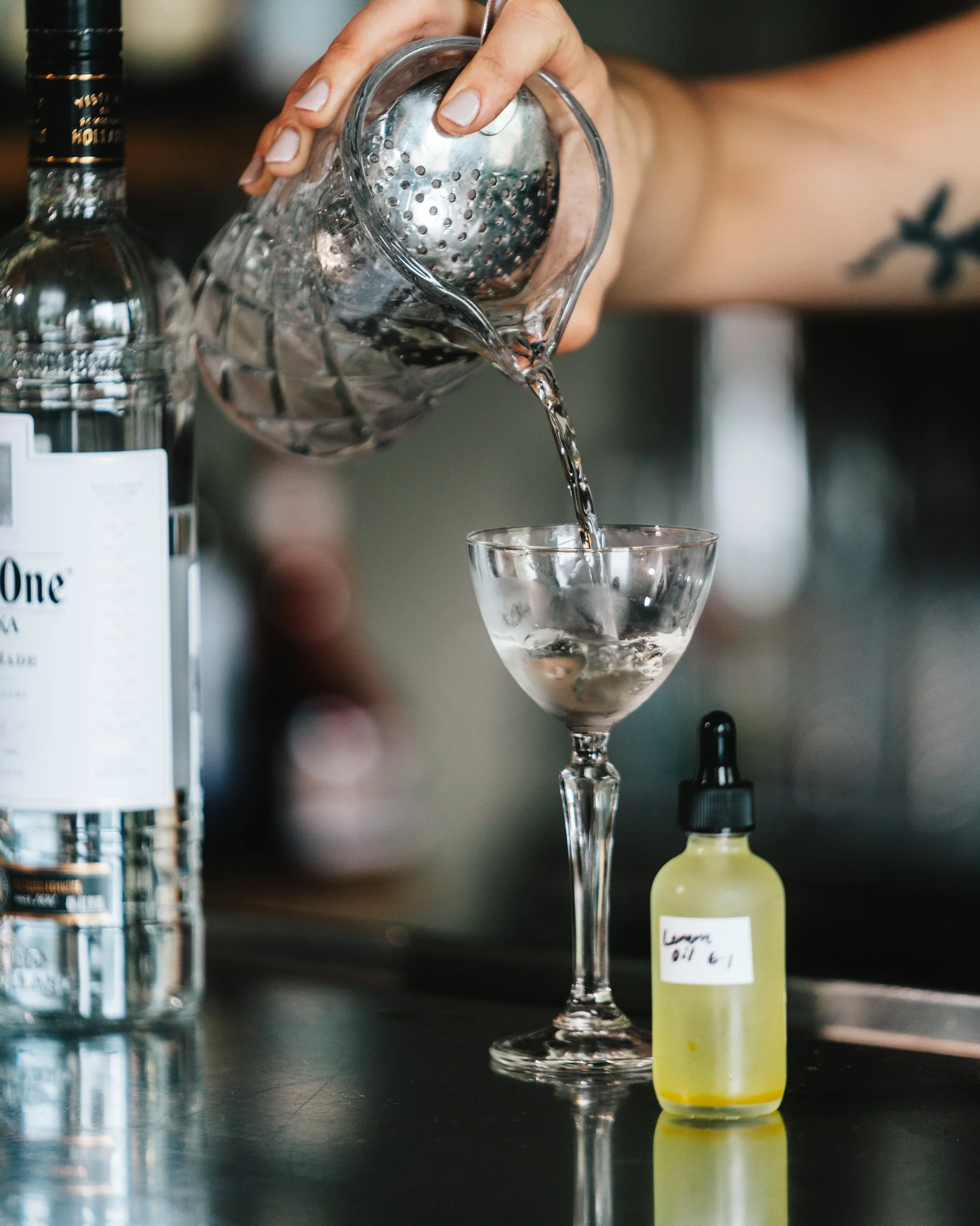 pouring a cocktail into a nick and nora glass