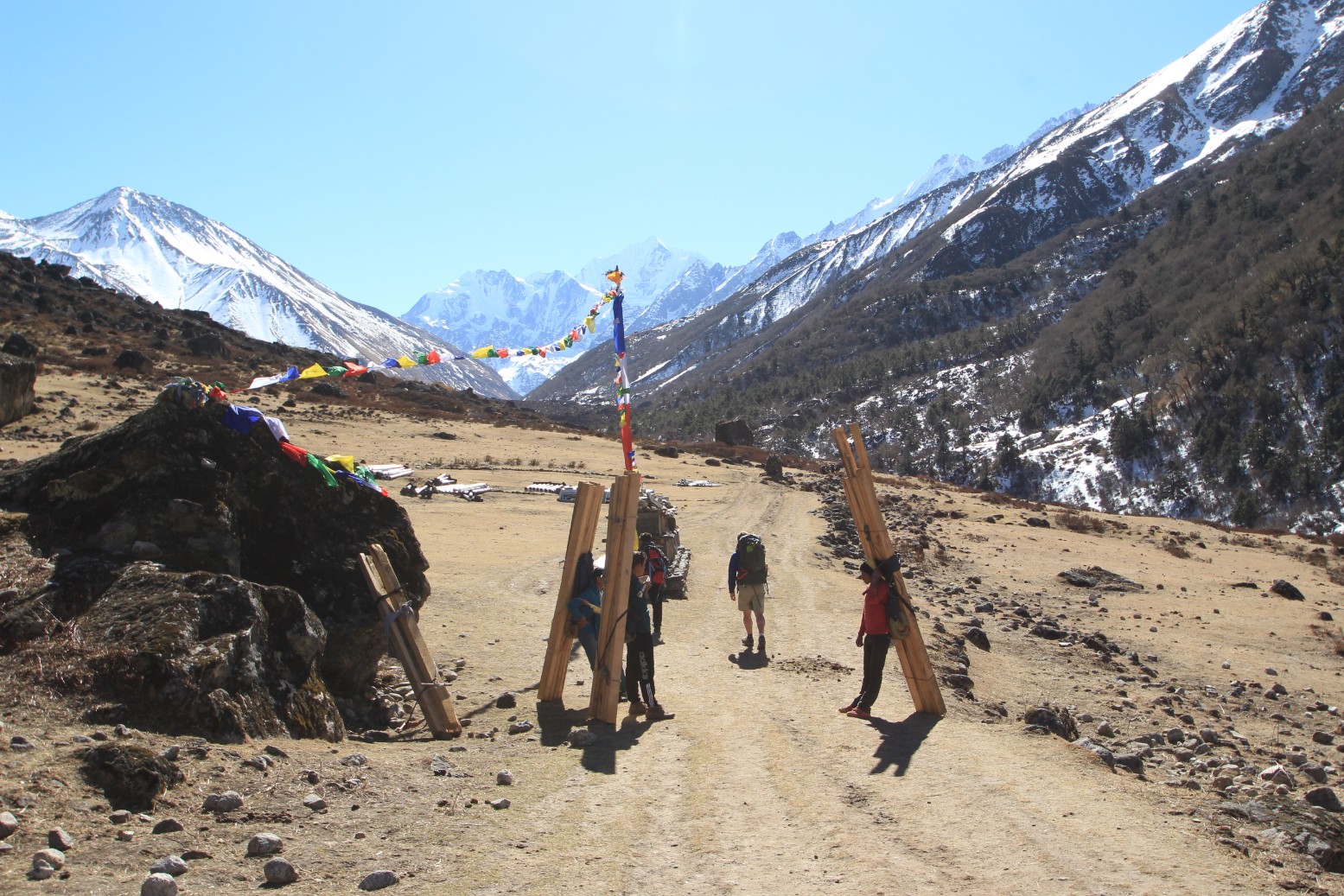 Porters carrying 4x4 posts up the valley