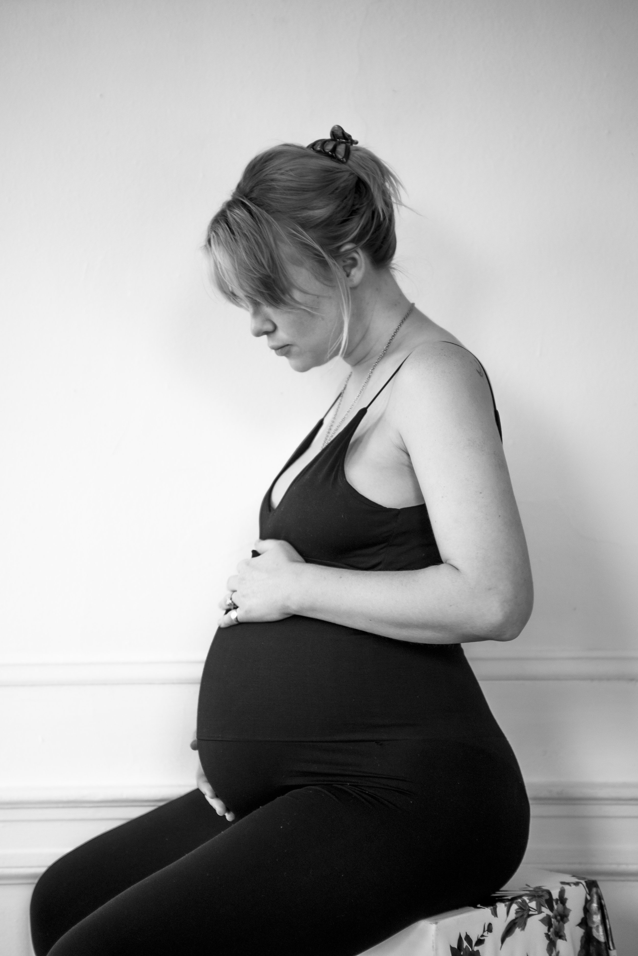 Woman embracing her baby bump looking and sitting down.