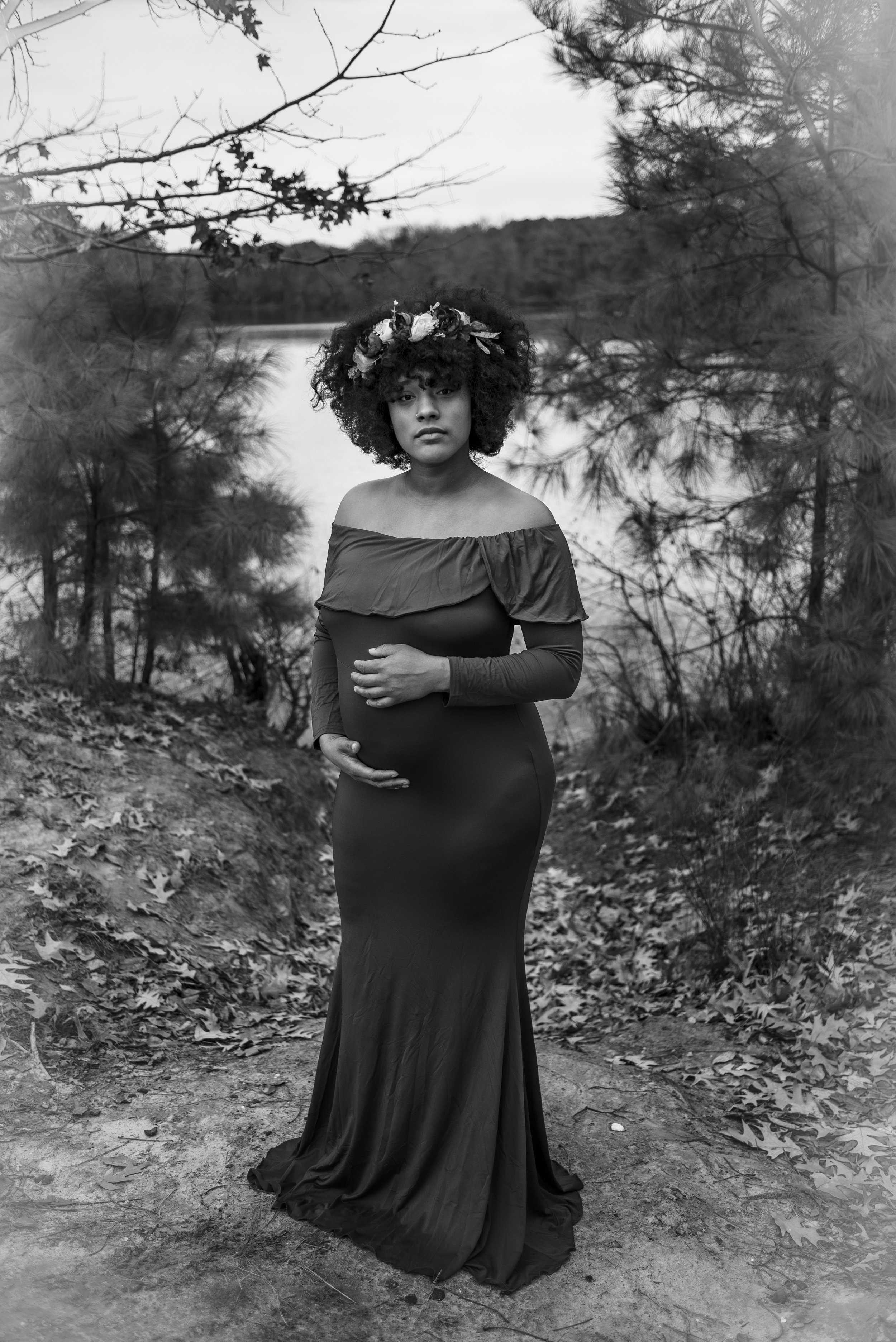 Woman embracing her baby bump in the forest.