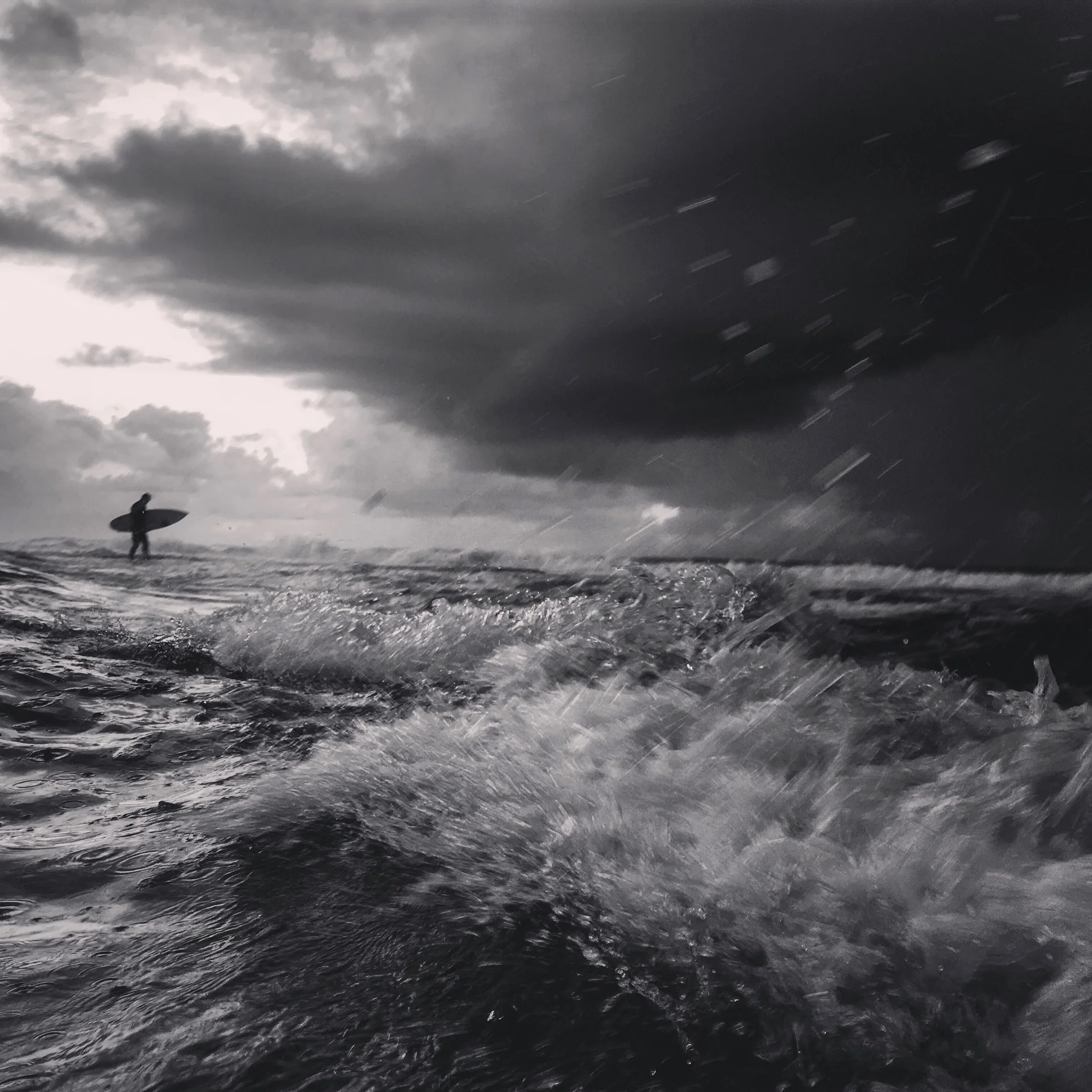 surfer-walks-out-to-ocean-on-stormy-day-by-newcastle-portrait-photographer.jpg