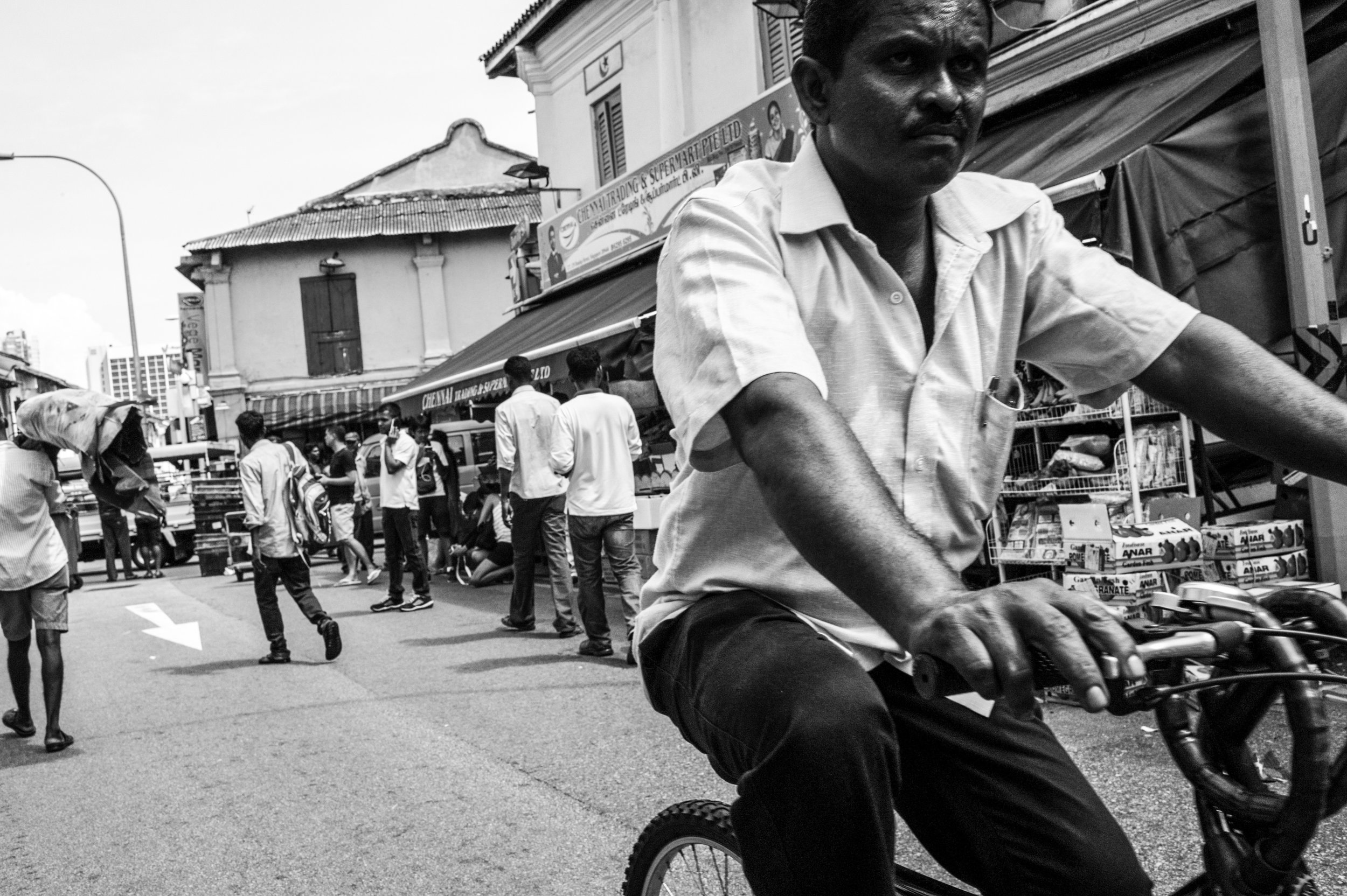   Street bazaar . A cyclist passes through one of the busiest streets in Little India where food, groceries and supplies are sold and serviced mainly to migrant workers. 
