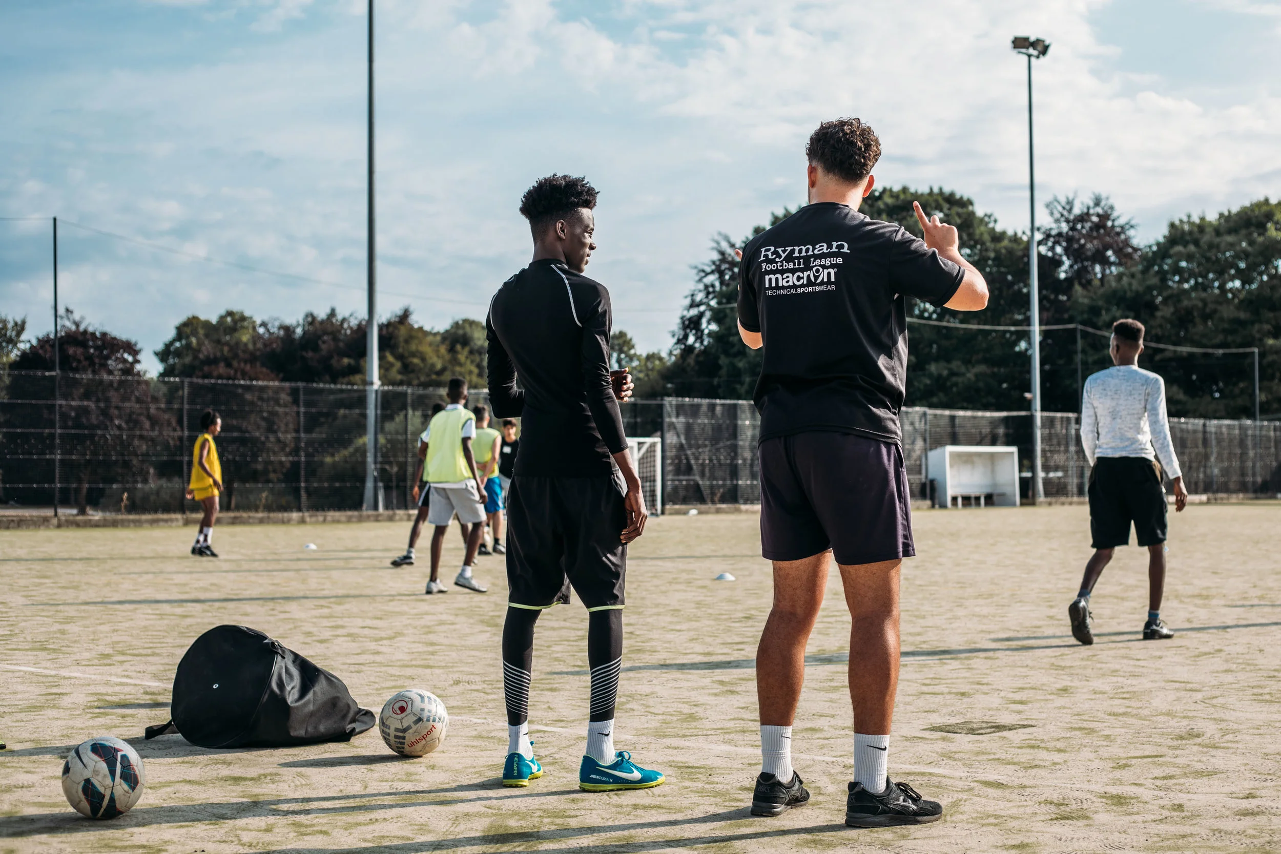Volunteer coach Joss Hole talks offside with a Nations United FC player on Chichester University football pitch. Nations United FC is a football team made up entirely of refugees - set up earlier this year by volunteer group Sanctuary in Chichester. The team has players from around 8 nationalities and was started to help integrate young refugees in West Sussex into the community. 20th July 2018.