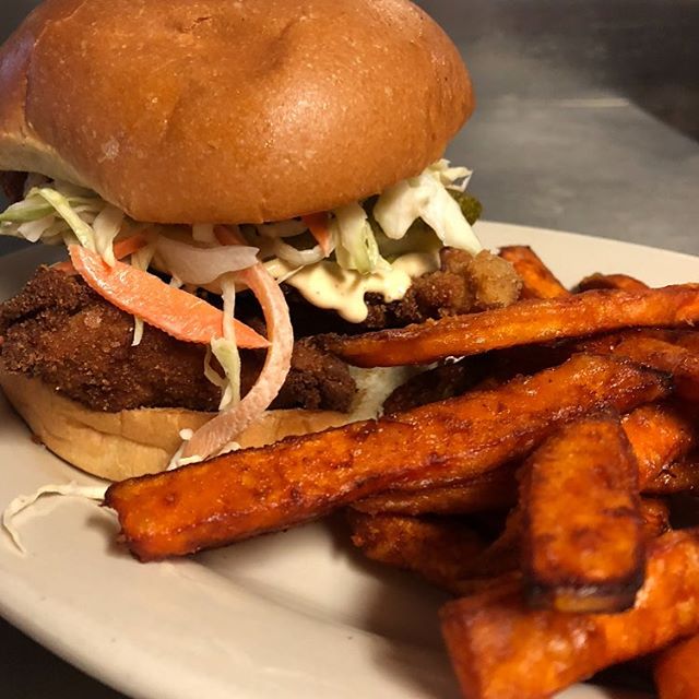 Buttermilk fried chicken sandwich with sliced pickles and slaw on a brioche roll.