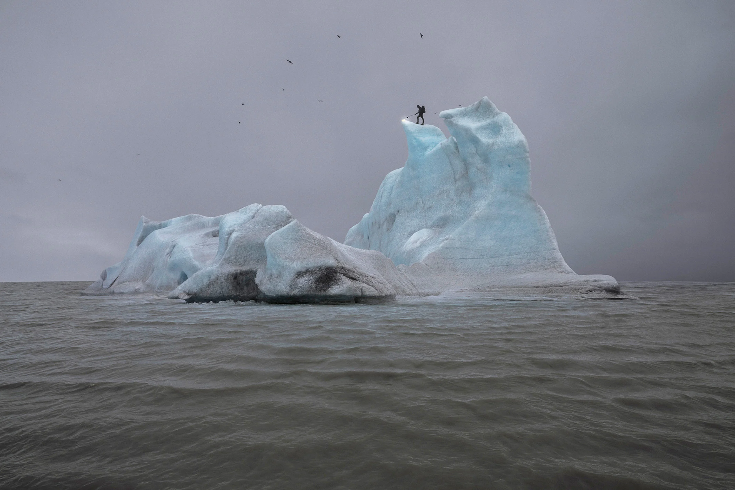 The Blue Fossil Entropic Stories, Julian Charrière The Blue Fossil Entropic Stories is the photographic trace of an artistic intervention the artist staged in 2013, traveling to Iceland to climb an iceberg in the Arctic Ocean and melt the frozen water beneath his feet with a gas torch for eight hours. Like an absurd, quixotic hero, Julian Charrière confronts the elements in a seemingly hopeless battle — human time against geological time. And yet, a battle of which global warming is only the starting point. What remains of this perilous endeavor are three photographs of arresting beauty, a kind of contemporary version of Caspar David Friedrich’s Wanderer Overlooking the Sea of Fog (1817-1818), and a questioning of our relation to nature as inherited from the Romantics via ecological thought.