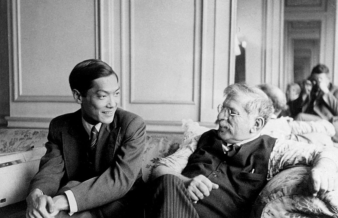 A black and white photo of Li Shiu Tong and Magnus Hirschfeld sitting on a couch in an ornate room at the fourth conference of the World League for Sexual Reform.