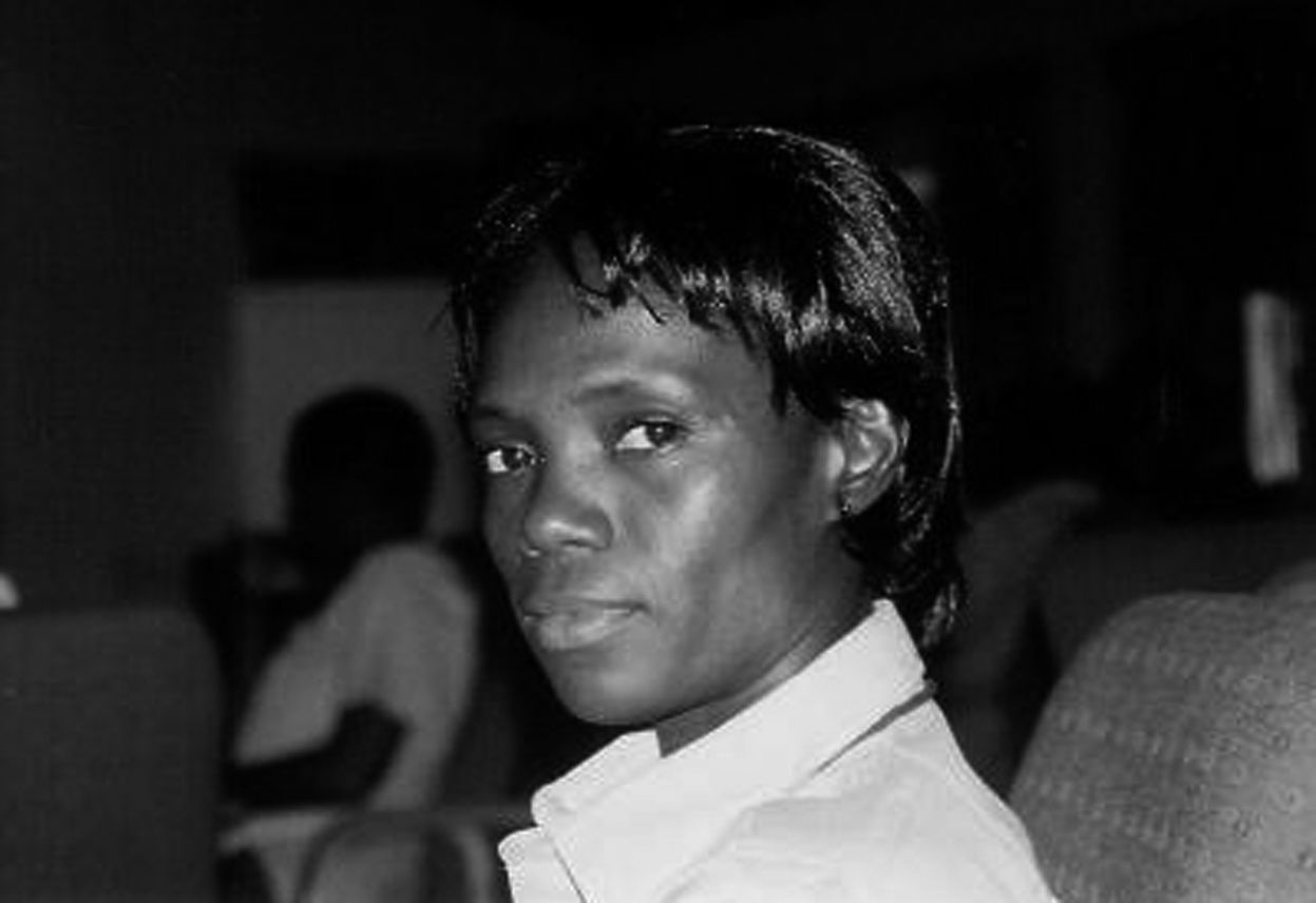 A black and white photo of FannyAnn Eddy, dark skinned black woman with a black pixie cut. She wears a white collared button up and looks thoughtfully at the camera.
